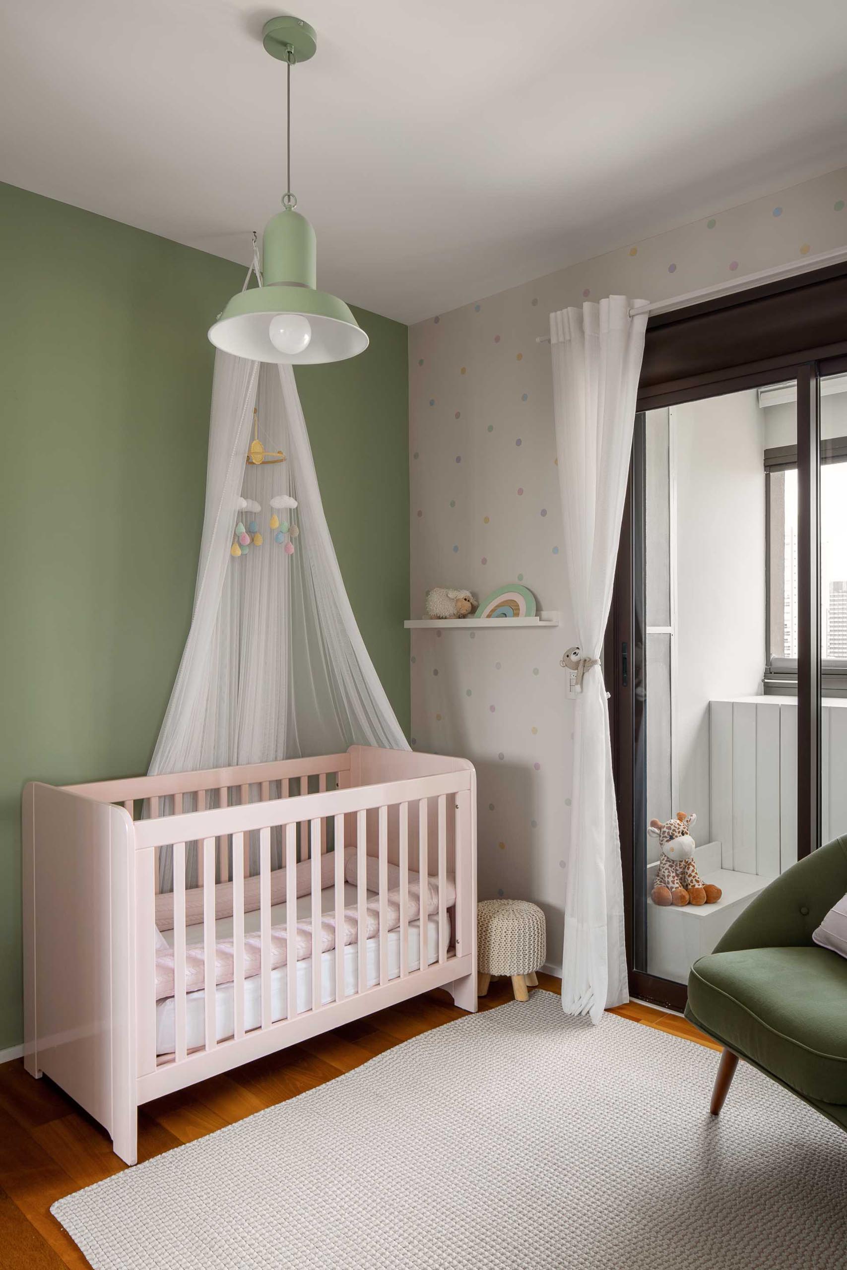 A modern nursery with a light green accent wall that stands out against pale pink crib.