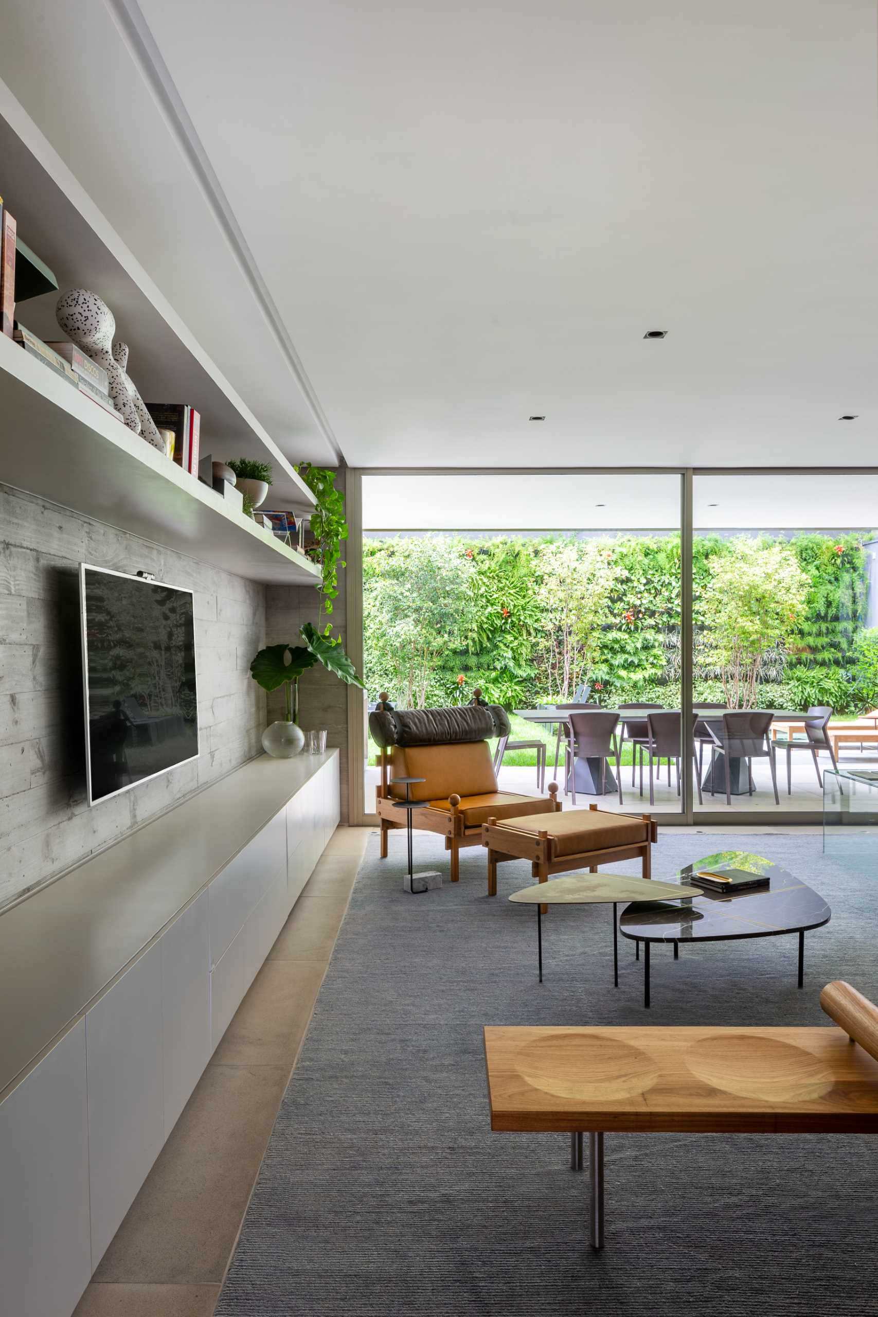 The furniture in this modern living room faces a concrete wall that been designed with a row of cabinetry below the TV and two shelves above.