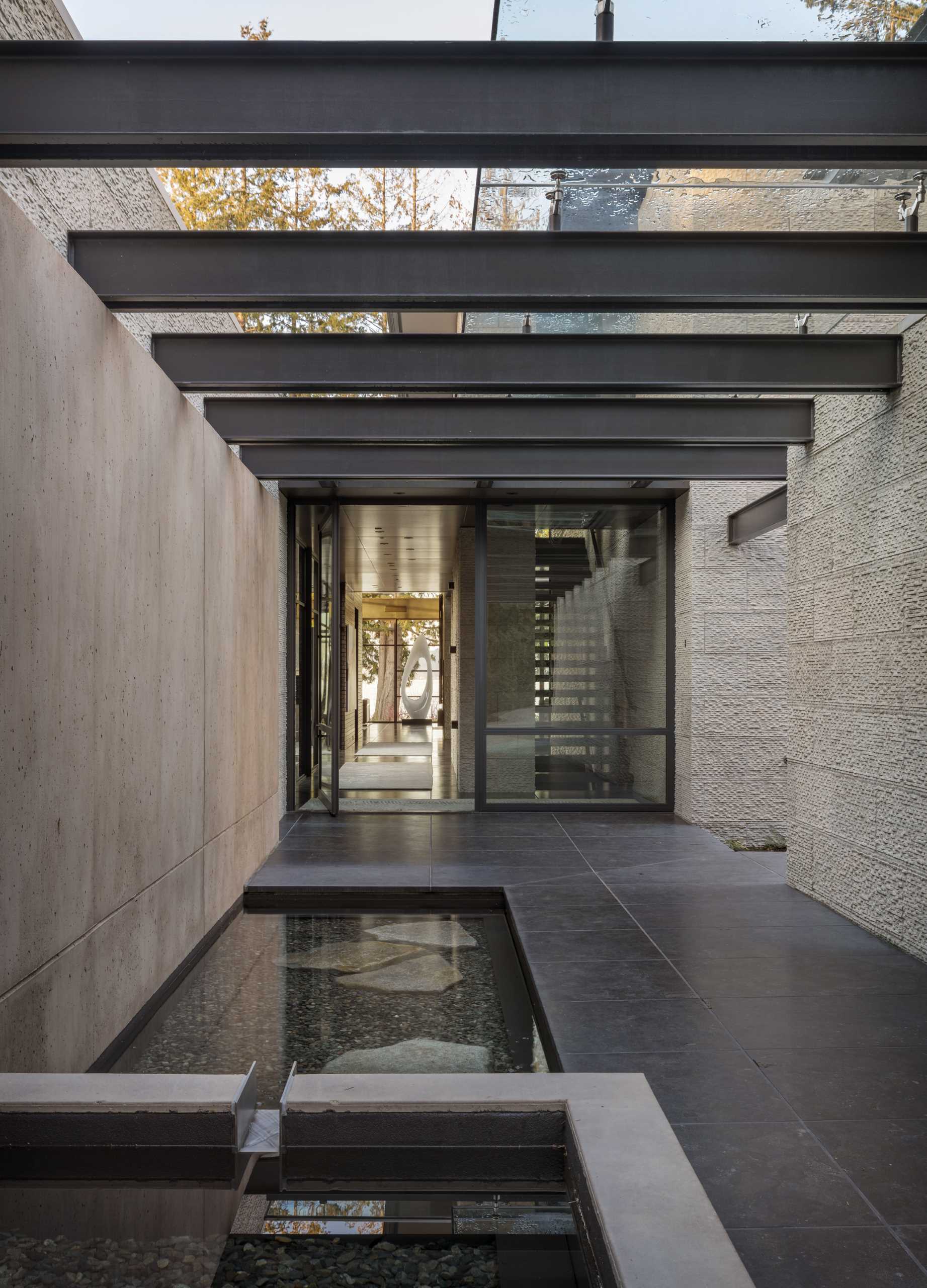 A modern house with a water feature that guides you to the front door.
