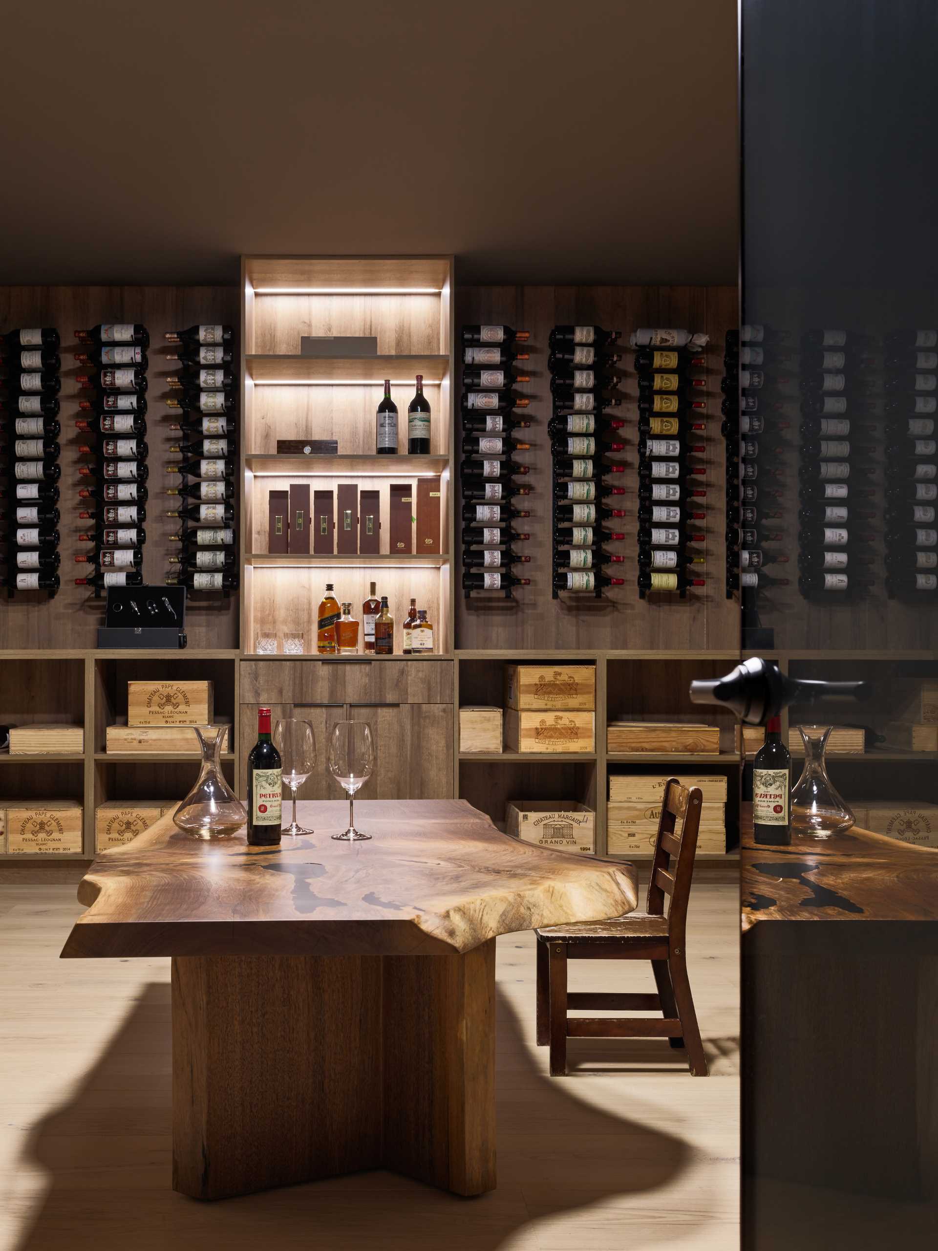 In this modern wine cellar, there's wall-mounted wine racks and below, there's open storage. A large live edge table adds a natural element to the space.