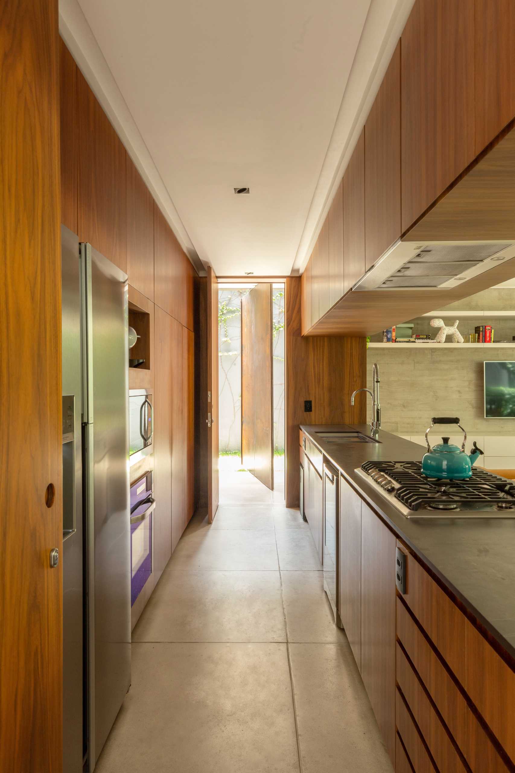 A narrow kitchen includes hardware free wood cabinets.