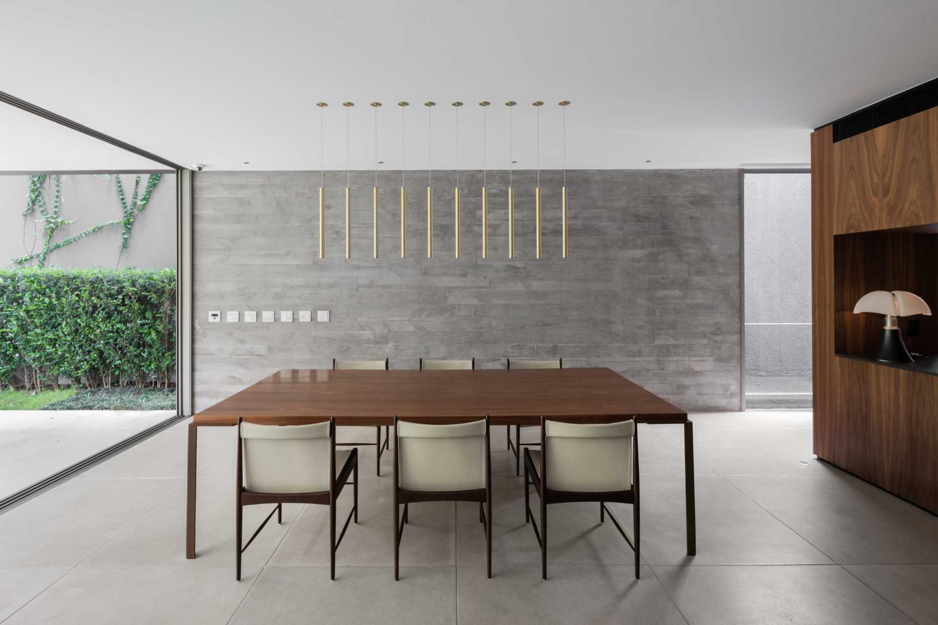 A concrete wall in this modern dining room, which has been left bare, and allows the minimalist pendant lights above the dining table to stand out.