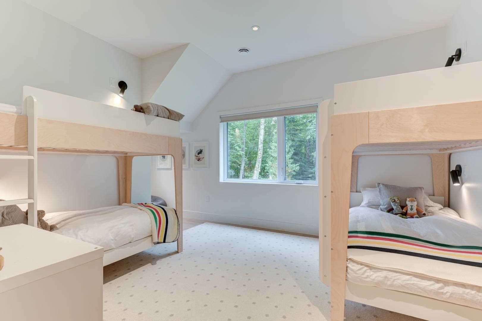 In this bedroom, two sets of bunk beds creates room for four to sleep. Each of the bunk beds also has their own sconce.