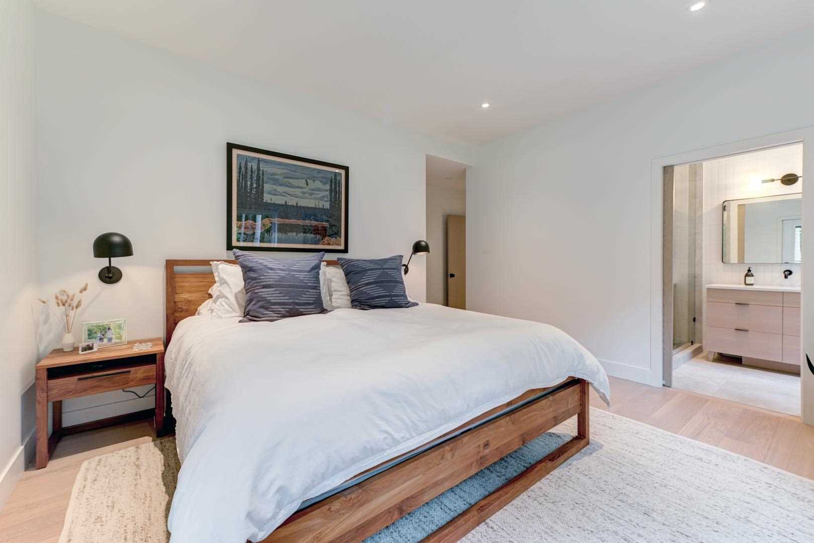 This bedroom has been kept minimal with artwork above the bed and black sconces.