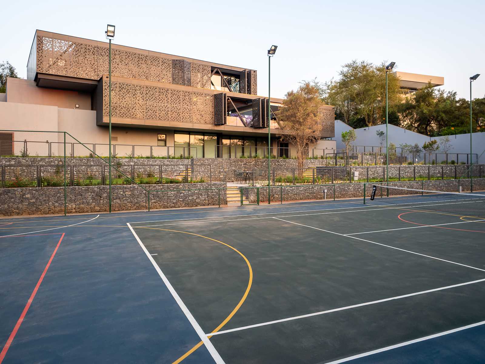 Metal screens wrap around this modern house, and on one side, they fold open to allow the sun and wind to pass through, When closed, the metal screens provide privacy and shade.