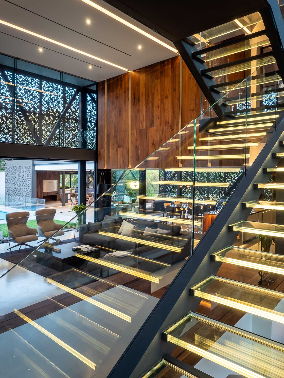 A glass staircase with hidden lighting connects the lower levels of this modern house with the more private areas upstairs.
