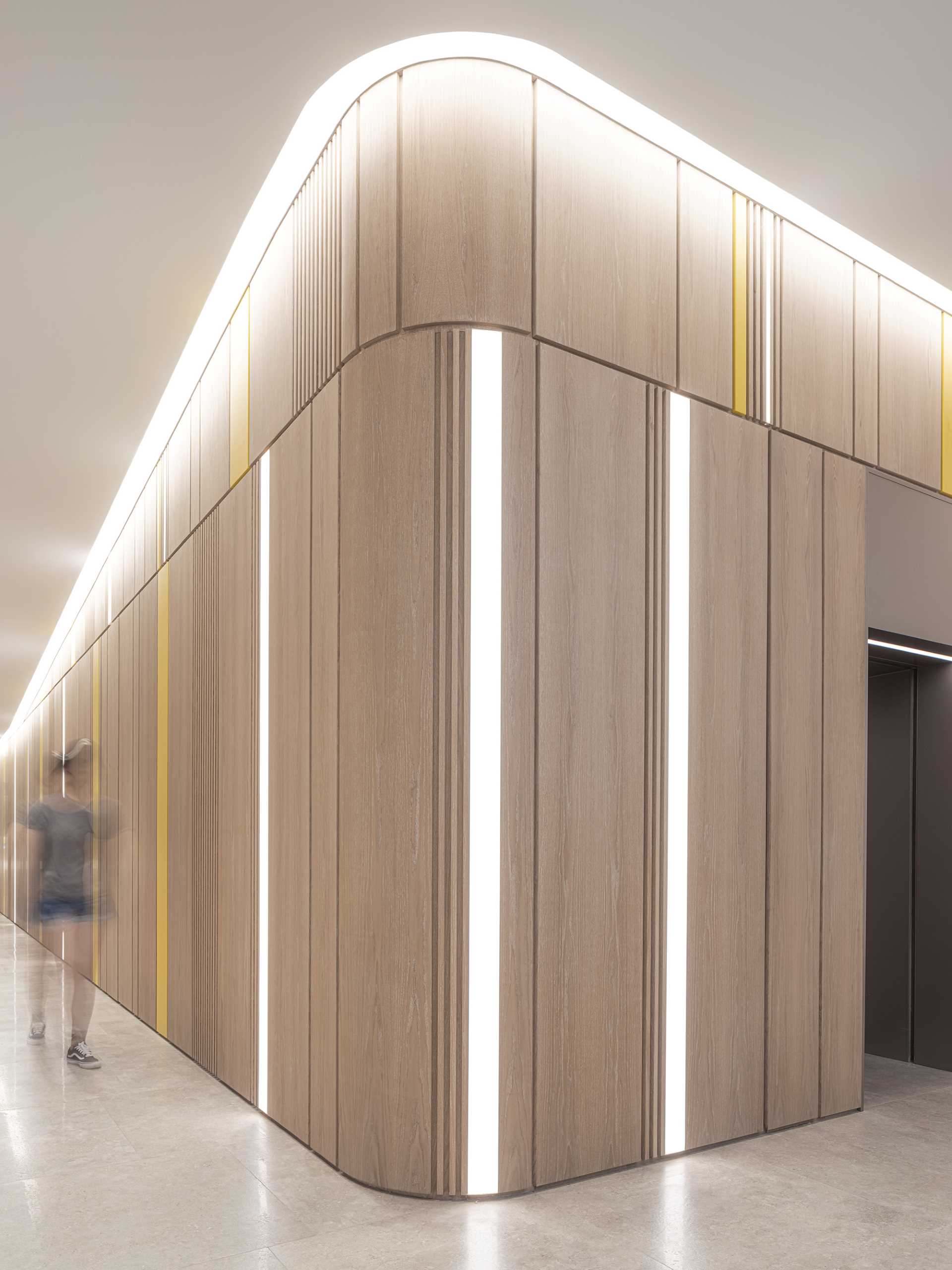 A wood wall that curves around the corners, includes hidden doors and vertical lights.