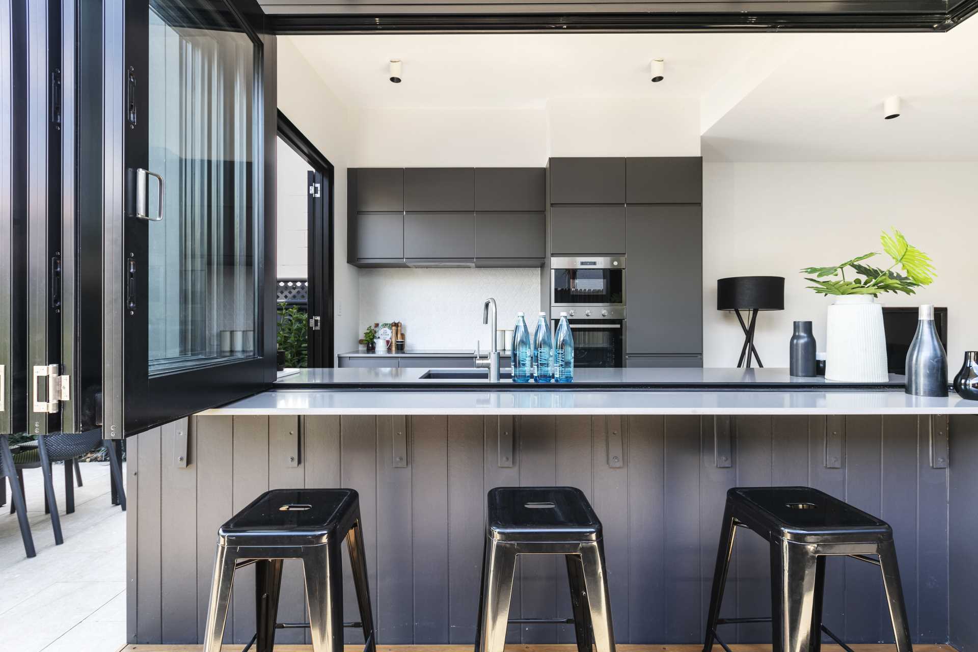 A modern kitchen opens to an outdoor bar area.