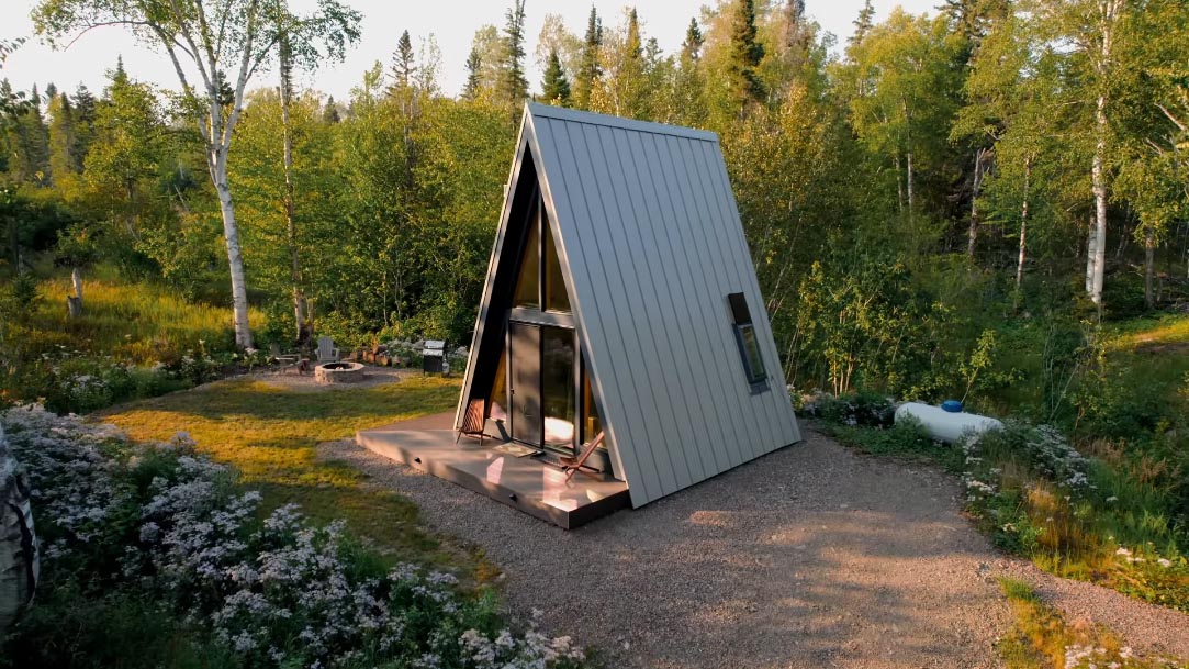 A modern A-frame cabin with a small deck.