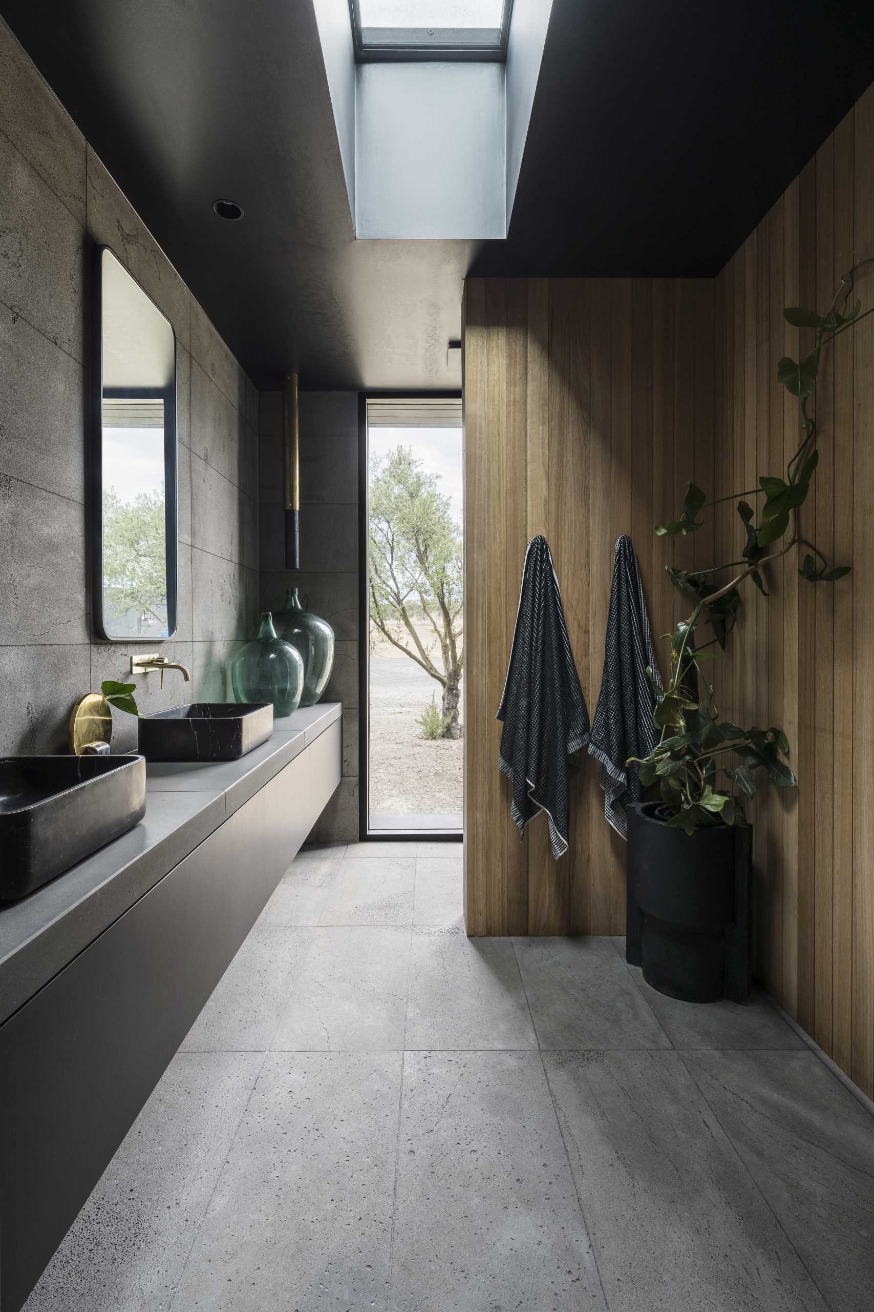 This modern bathroom features a floating black vanity, a skylight, and vertical wood accent walls.