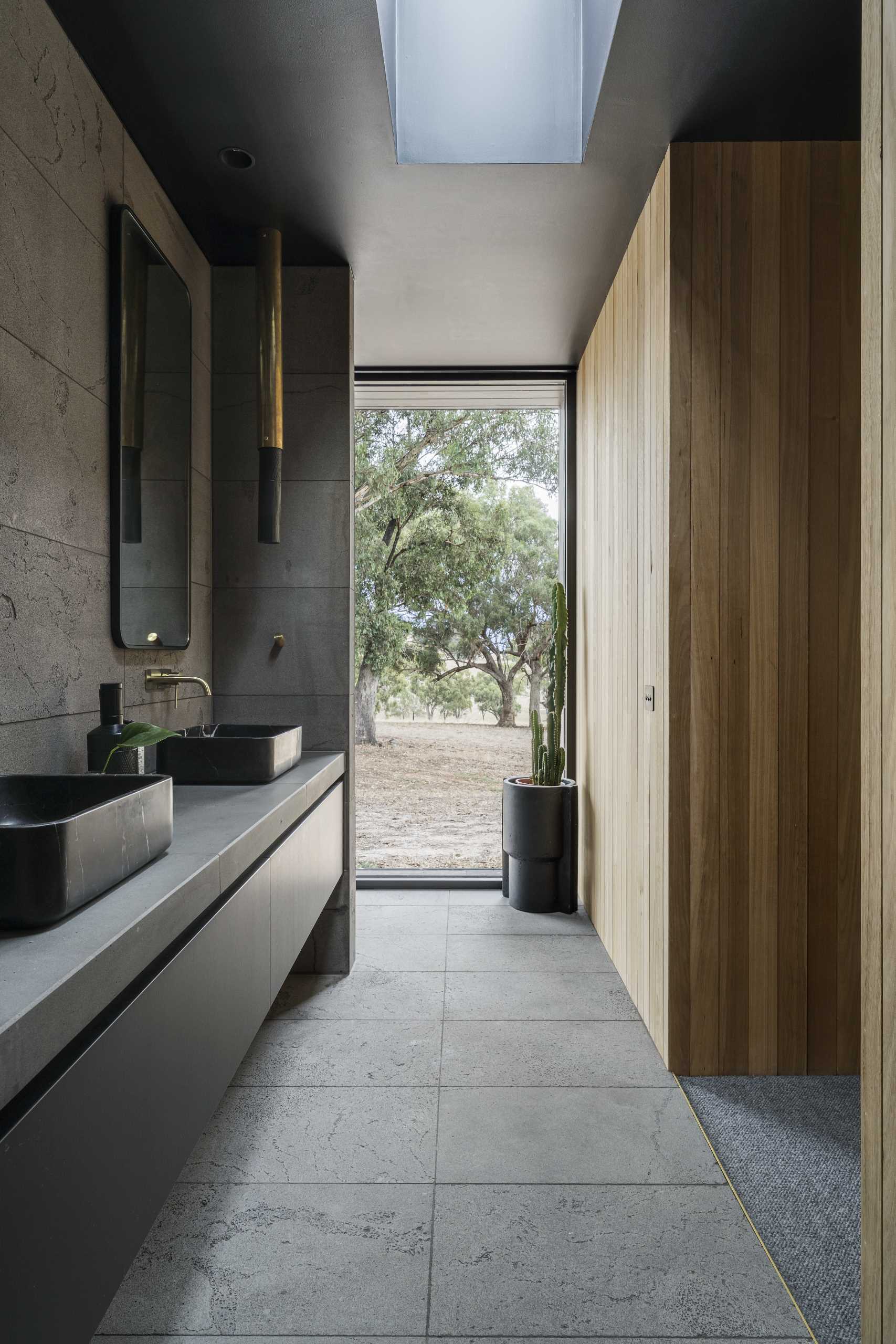 This modern bathroom features a floating black vanity, a skylight, and vertical wood accent walls.