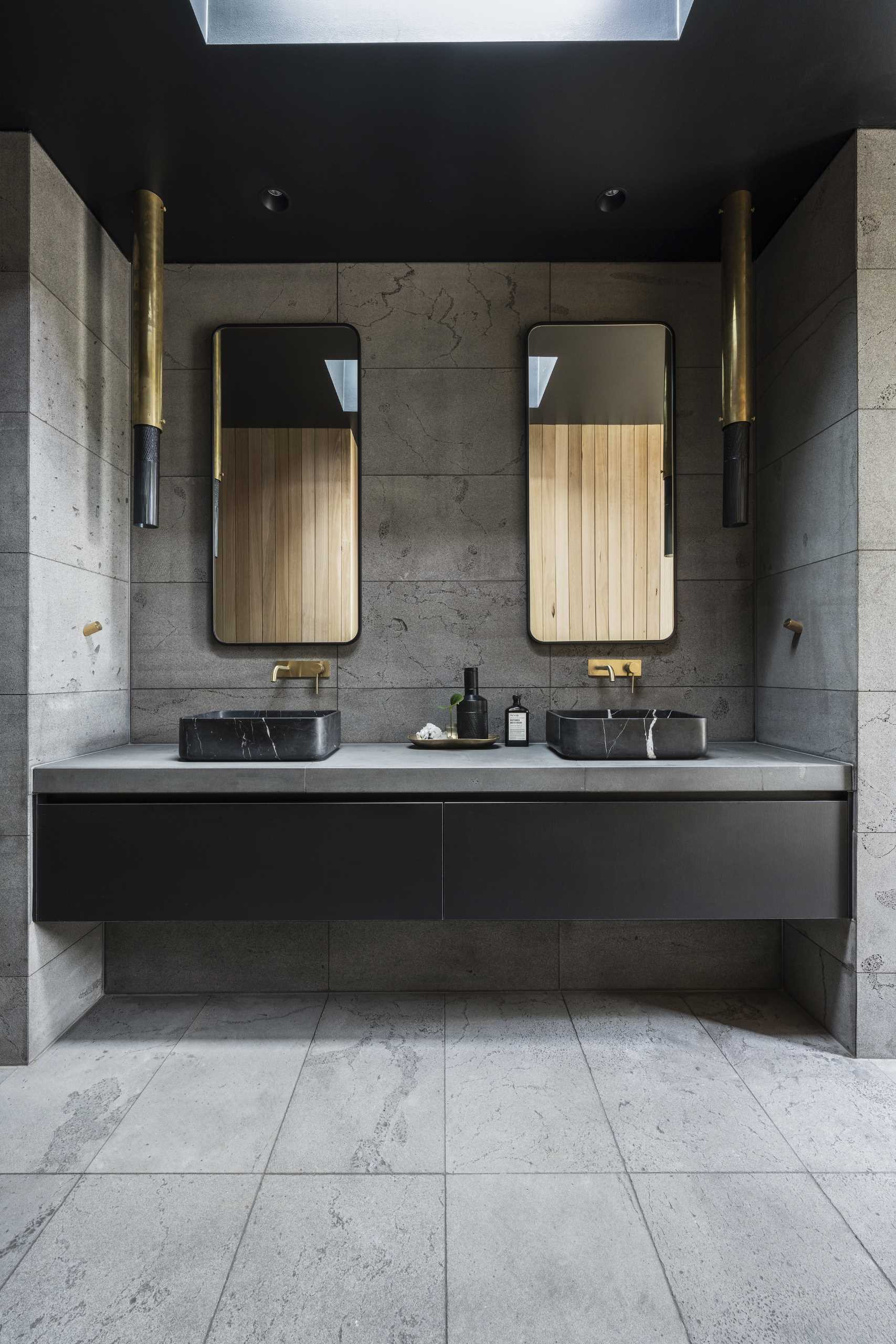 This modern bathroom features a floating black vanity, a skylight, and vertical wood accent walls.