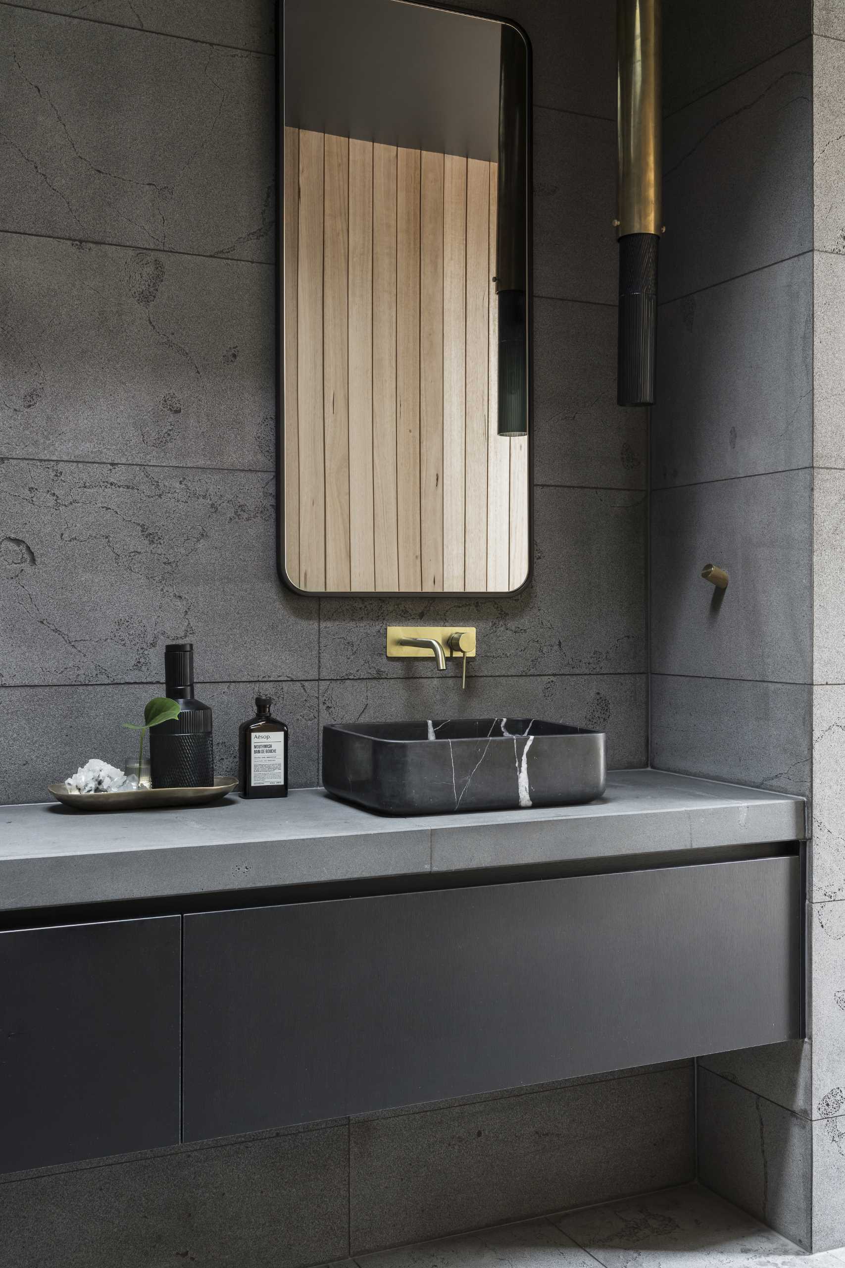 This modern bathroom features a floating black vanity, a skylight, and vertical wood accent walls.