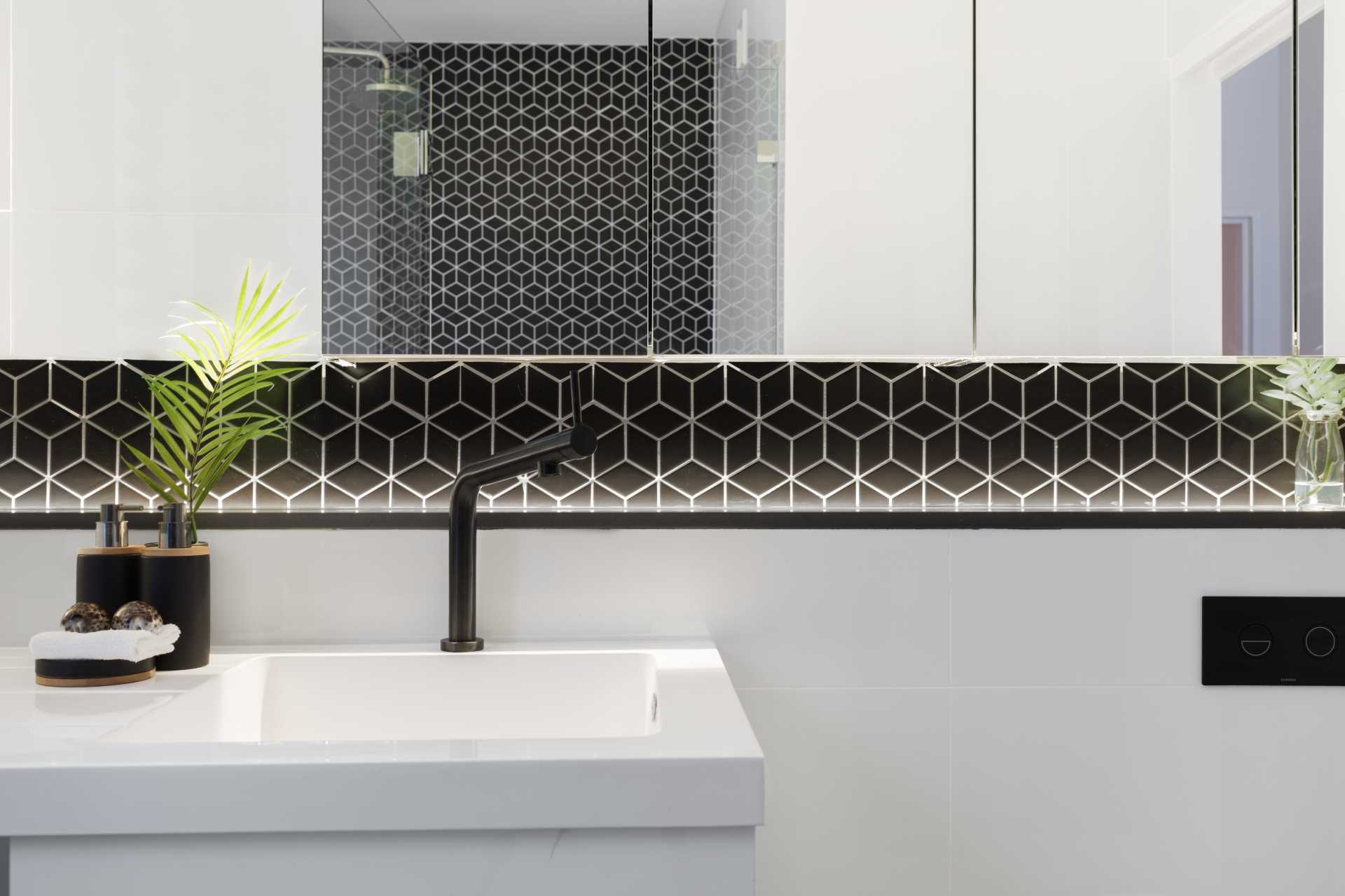 A modern bathroom with bold black geometric tiles.