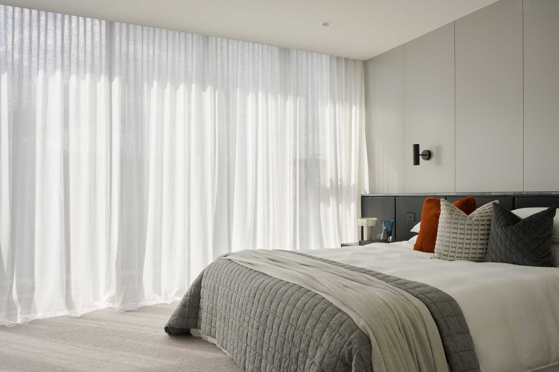 In this modern bedroom, a padded black headboard spans the room, while carpet is chosen flooring material.