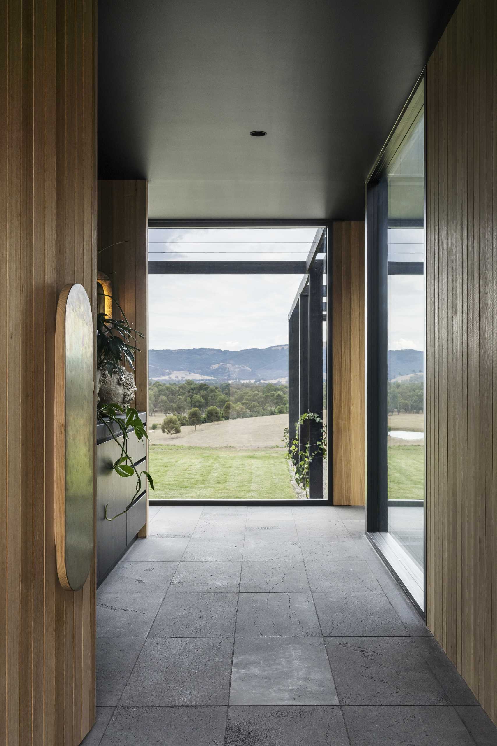 The interior of this modern home includes bluestone tiling, charcoal cabinetry and ceilings paired with rich timber cladding.