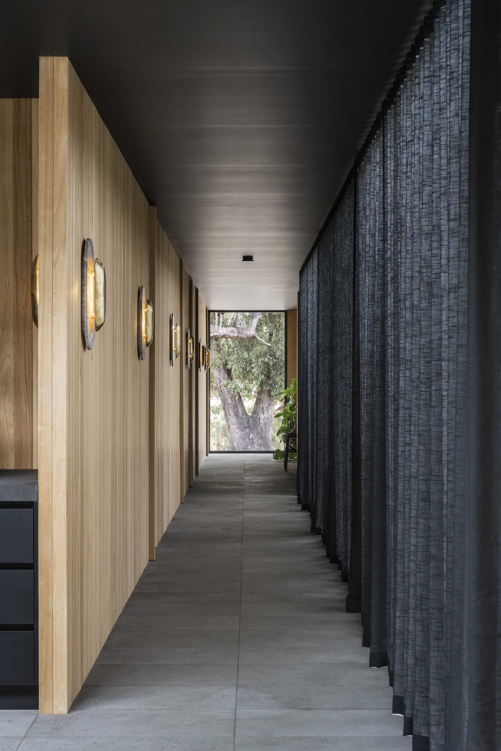 A modern hallway with a black ceiling, tile flooring, and vertical wood accent wall.