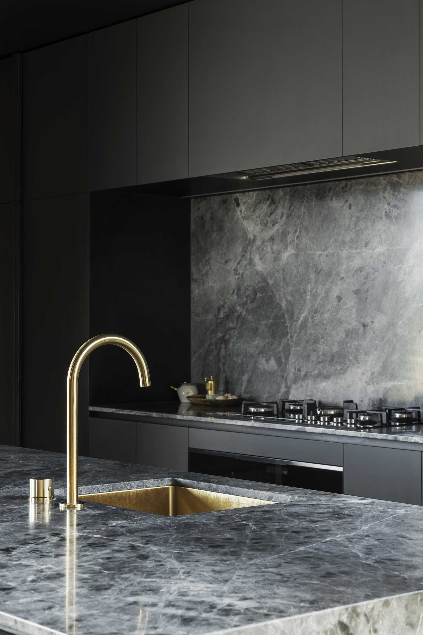 A modern black kitchen with brass accents.