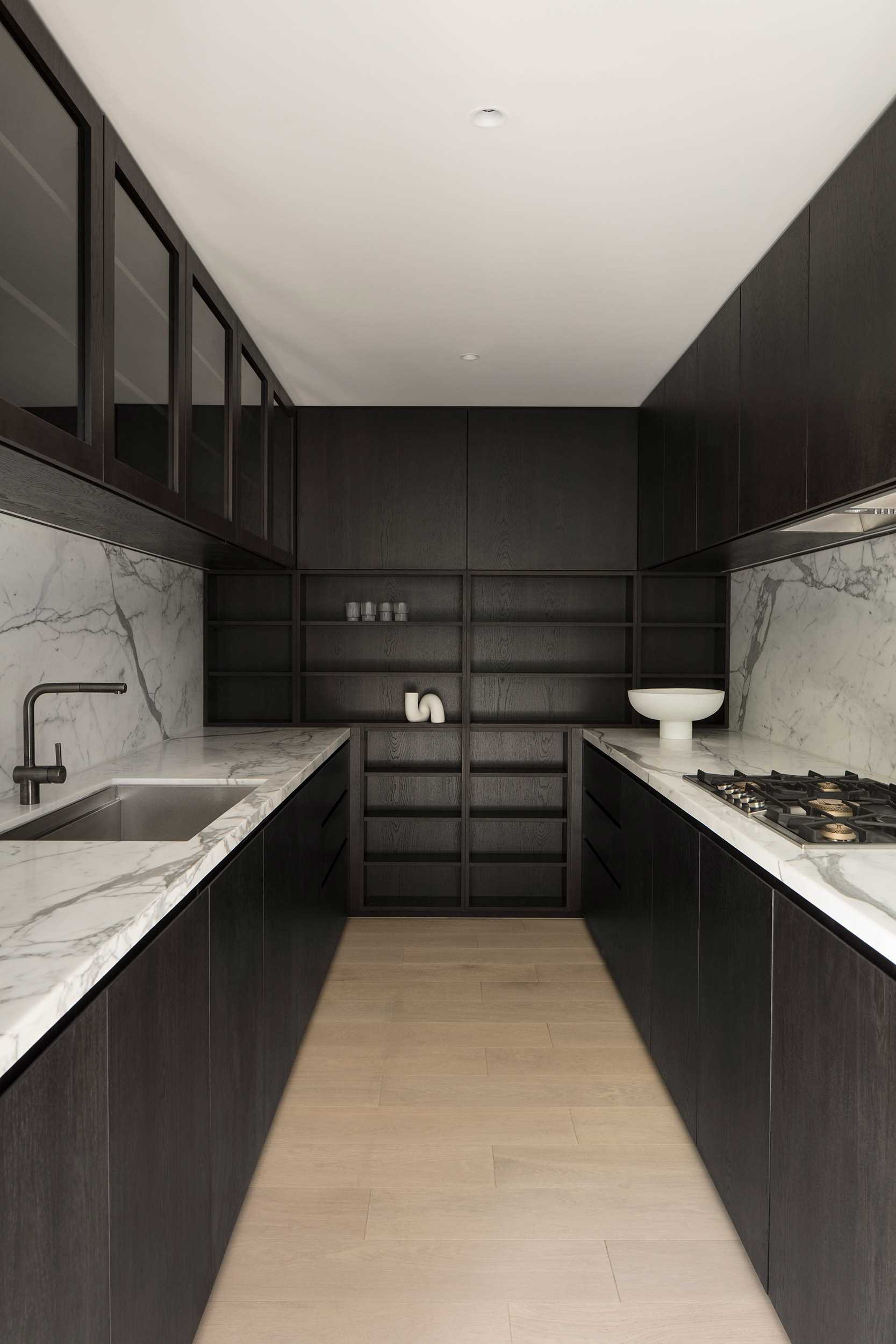 In this modern kitchen highly crafted joinery in natural timber and book-matched marble add to the overall feeling of warmth, contrast, and a refined approach to pared-down luxury.