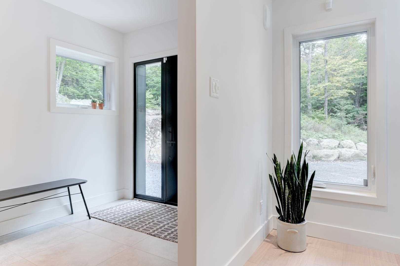 A simple entryway with a black front door and a minimalist bench.