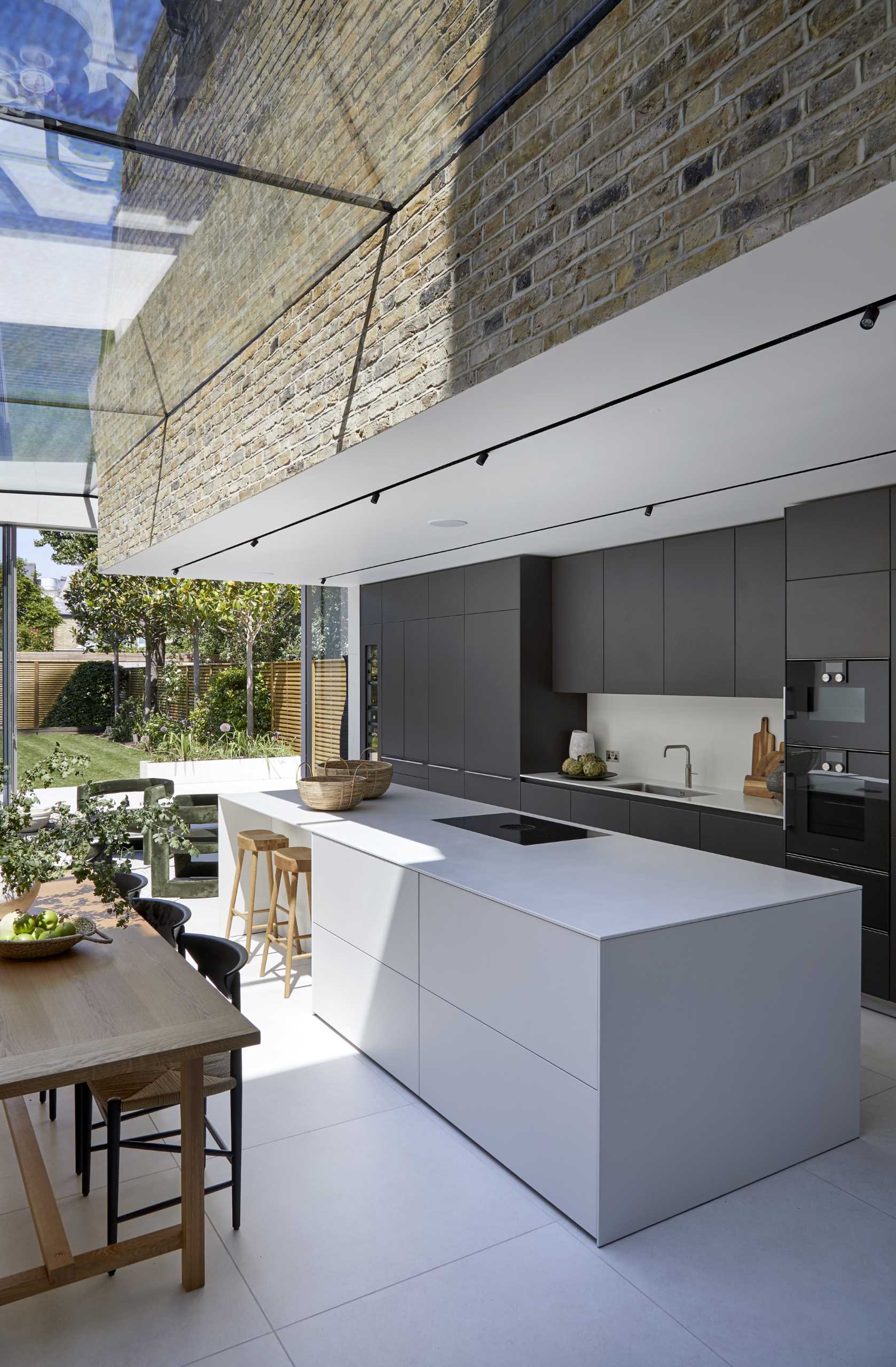 A modern kitchen with matte black cabinets, and a white backsplash and island.