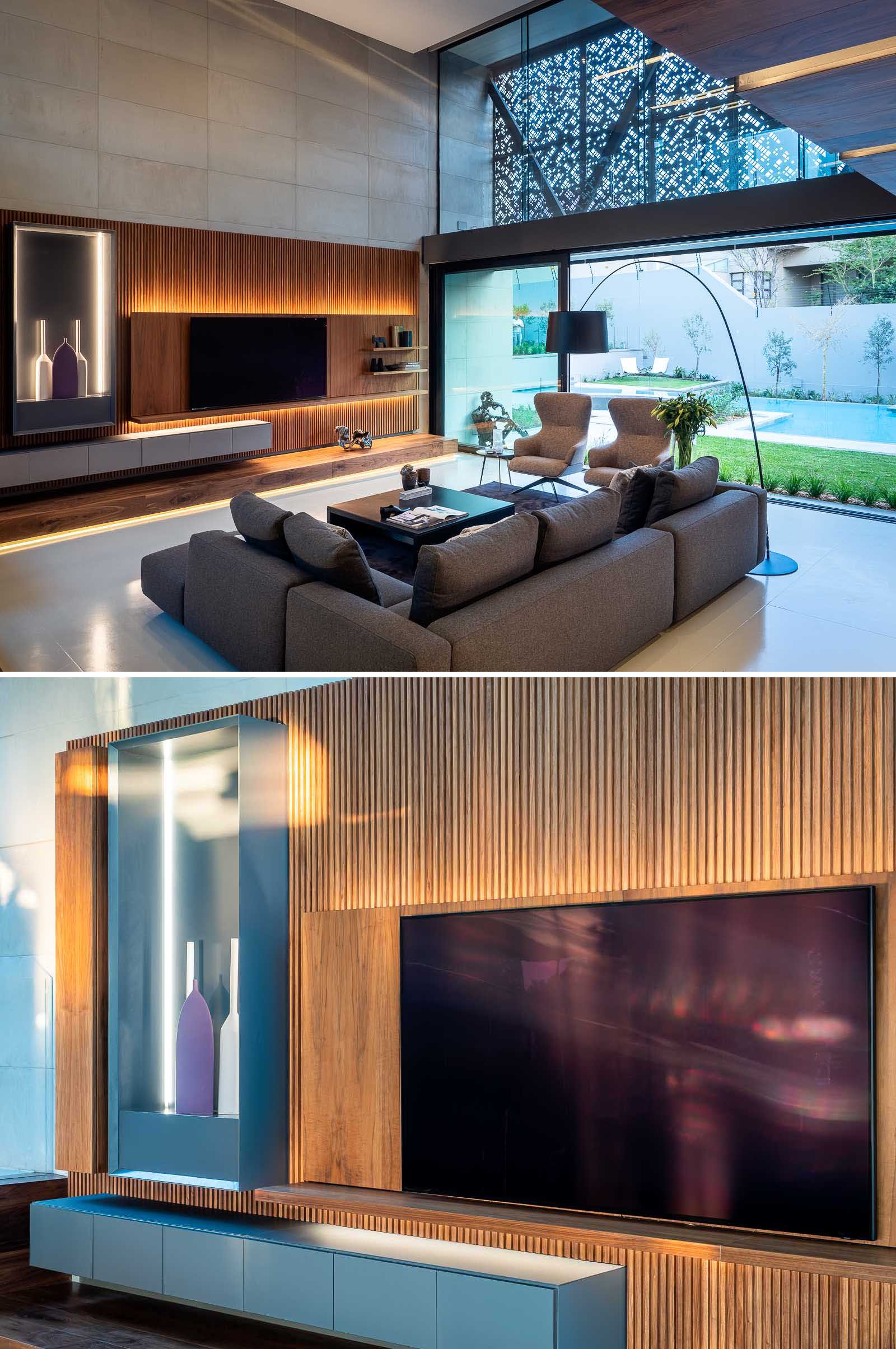 A modern living room with a wood accent wall that includes hidden lighting.