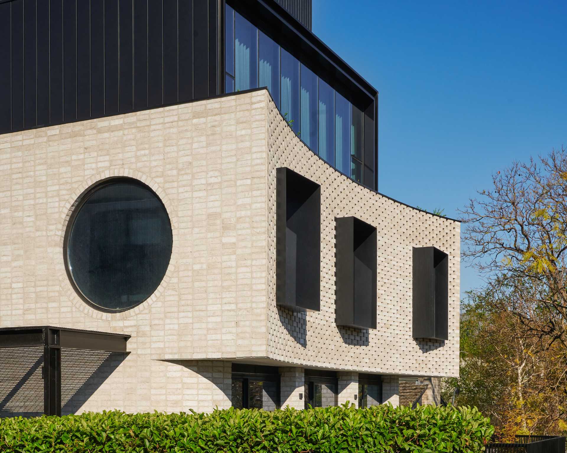A curved brick facade with protruding black window frames.
