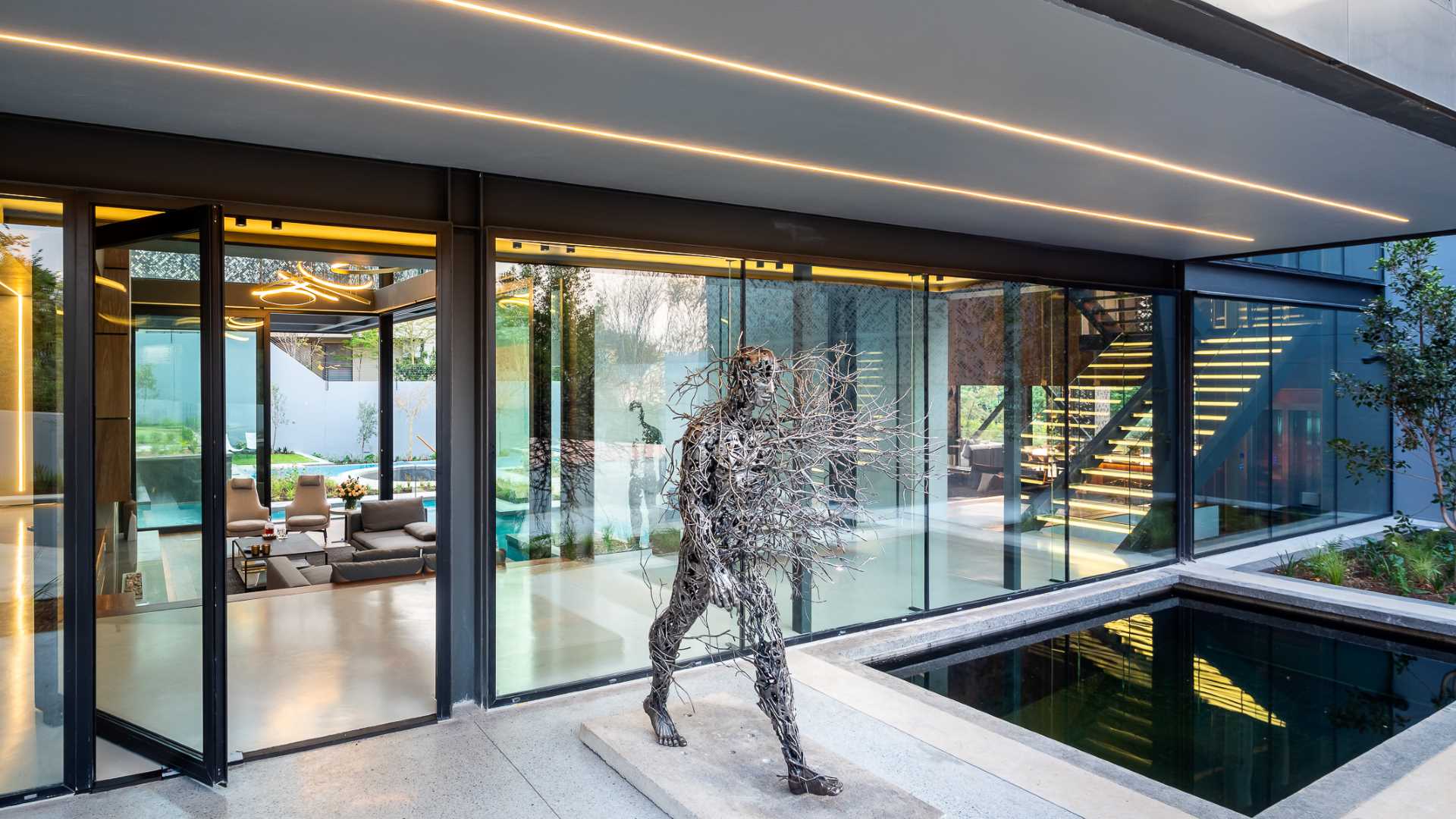 A modern glass entryway with a water feature and a metal sculpture.