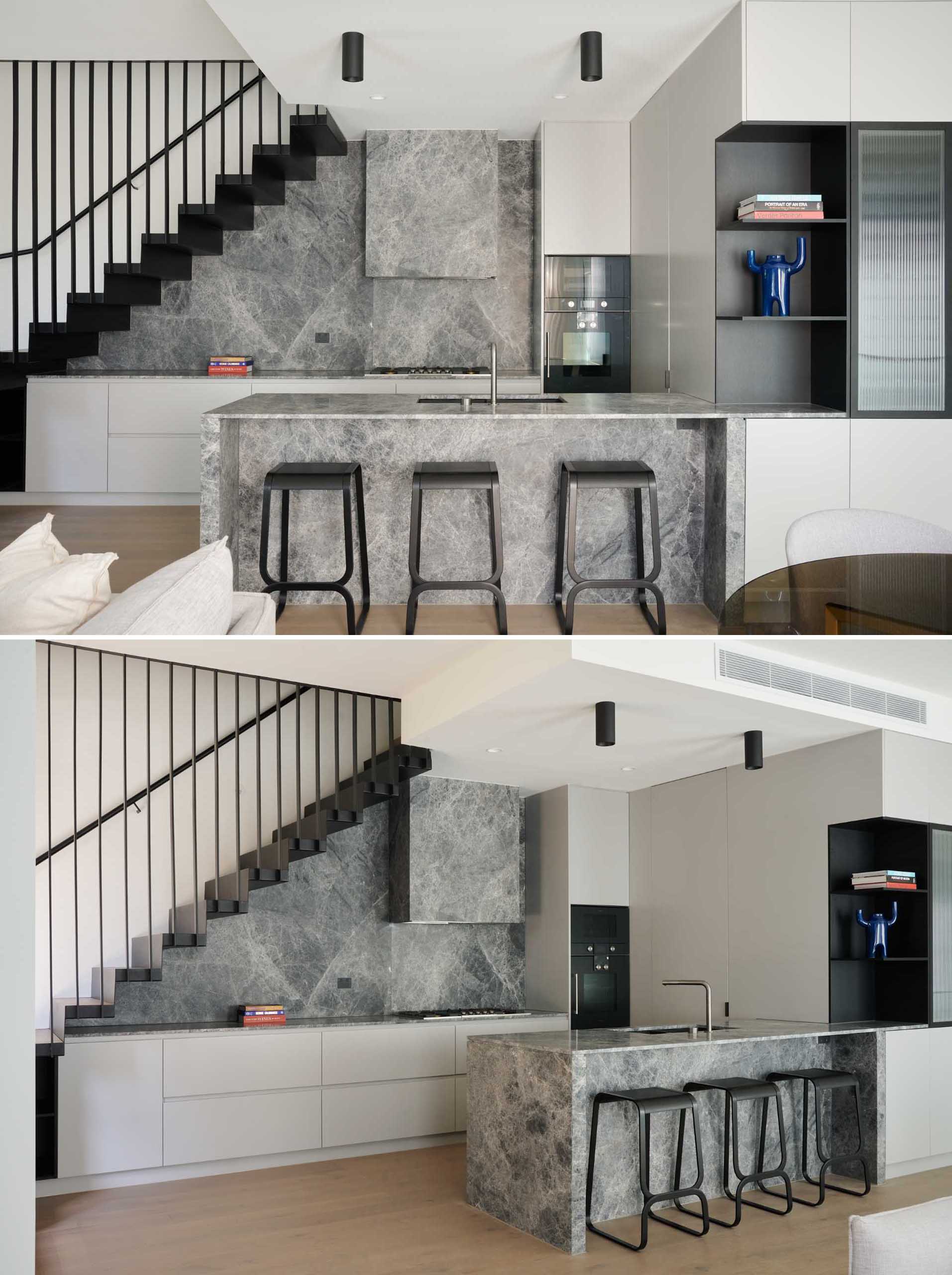 This modern kitchen, which is located underneath the stairs, and includes an island with counter seating, and minimalist hardware free cabinetry.