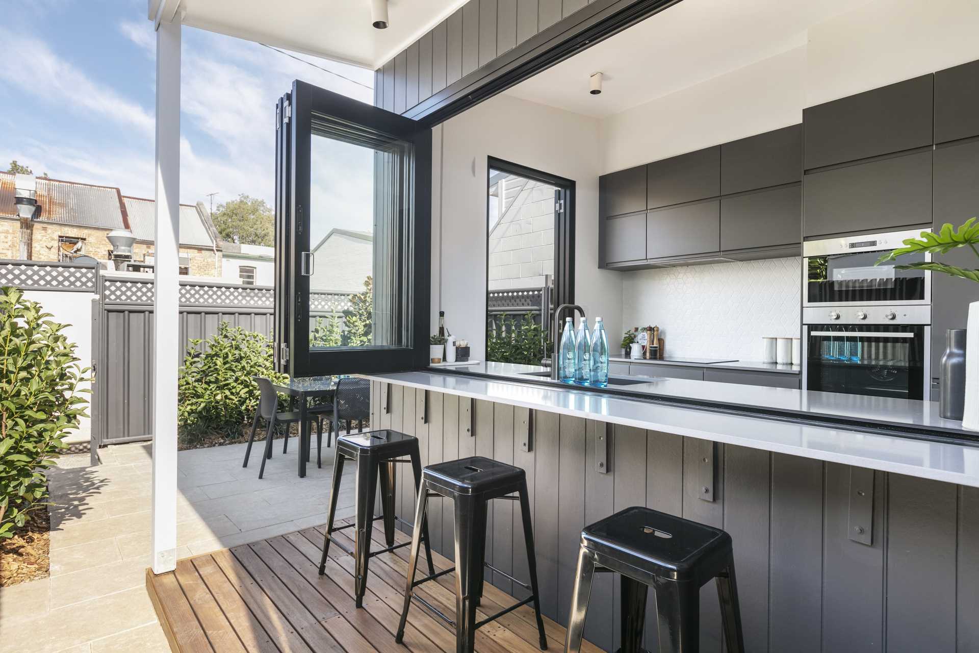 A modern kitchen opens to an outdoor bar area.