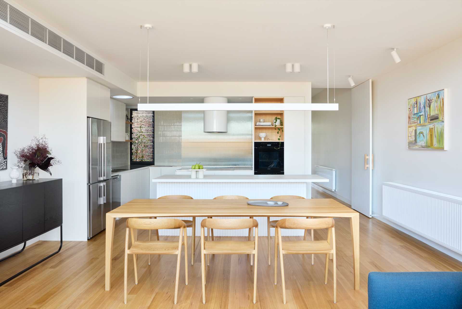 A modern interior with a dining area separating the living room and kitchen.