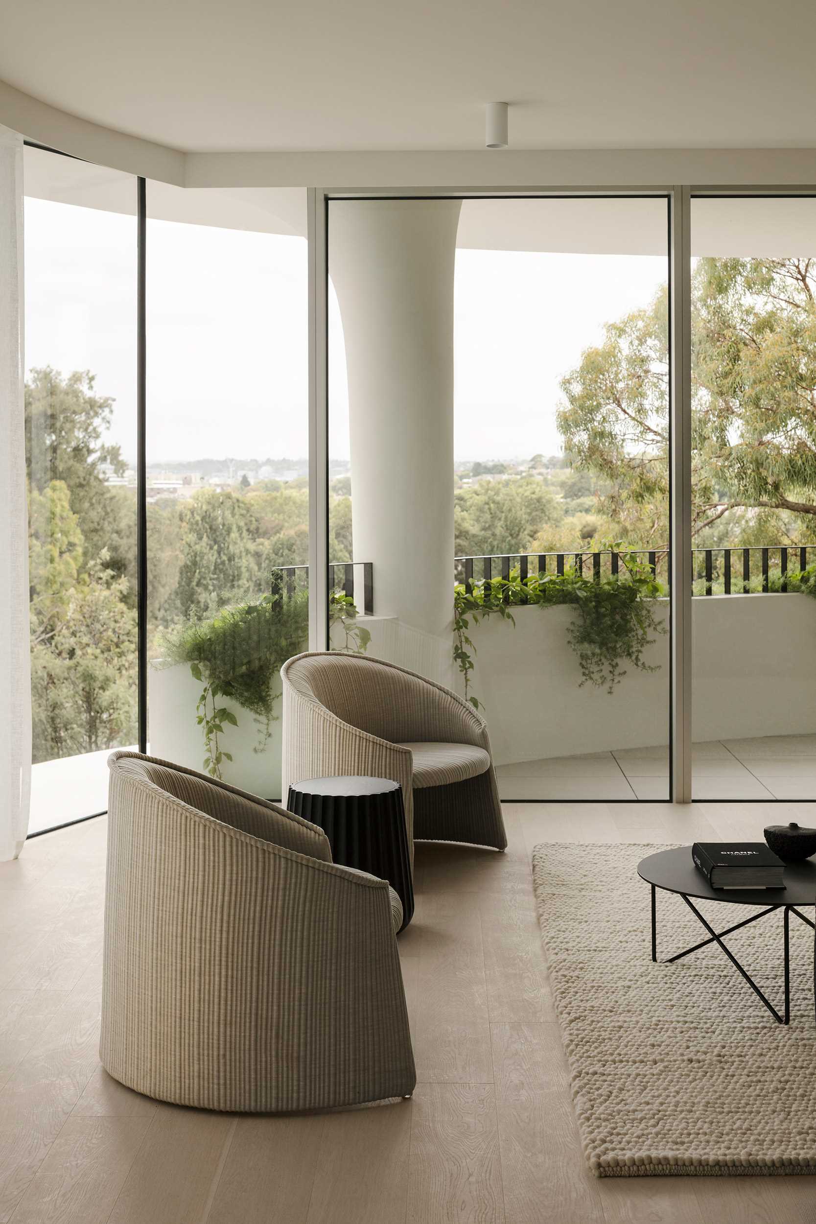 A modern apartment includes floor-to-ceiling windows, a curved terrace, a view of the structural fluted columns.