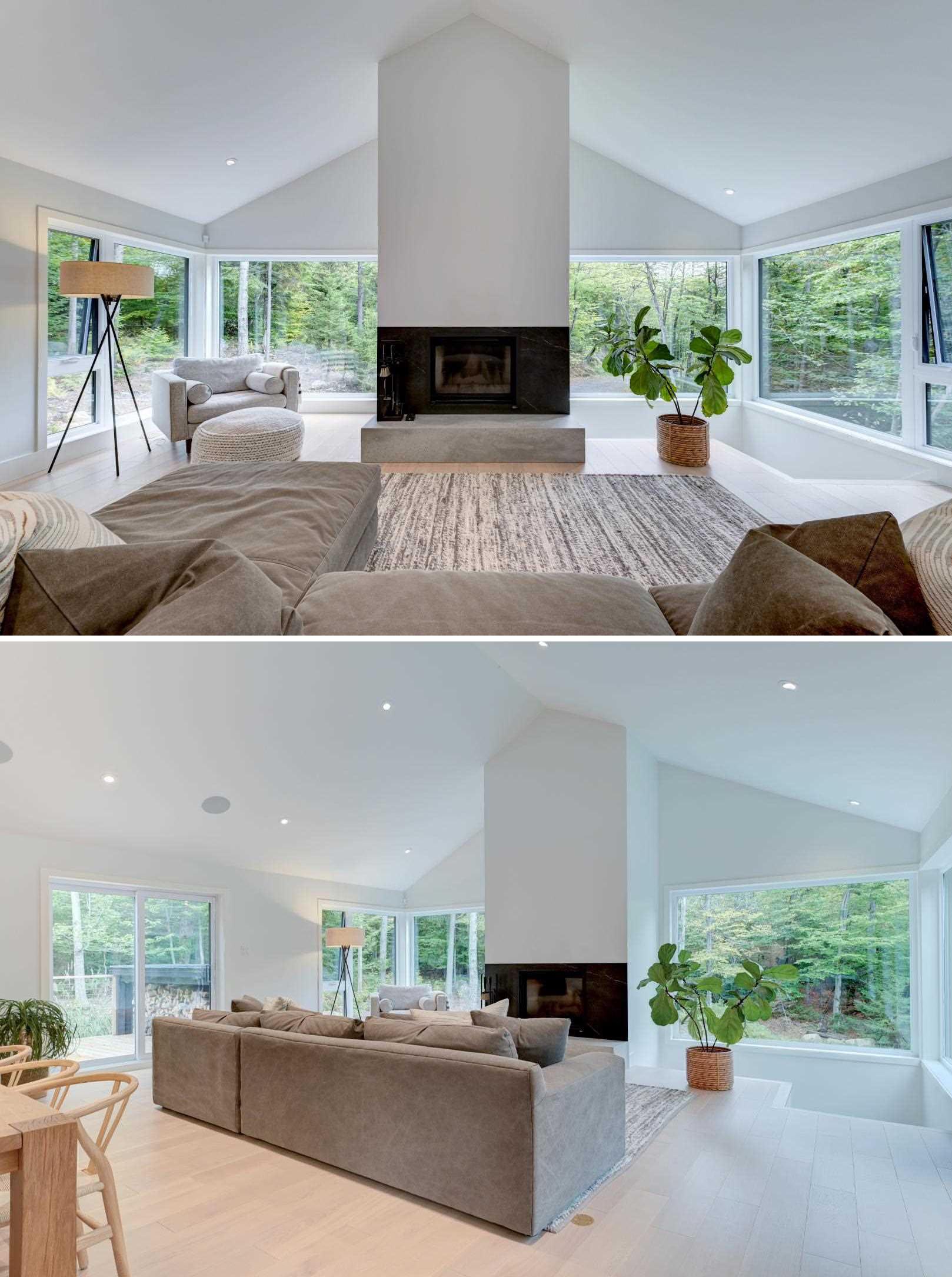 In this modern living room, large windows wrap around the room, while a fireplace draws the eye upwards to the cathedral ceiling.