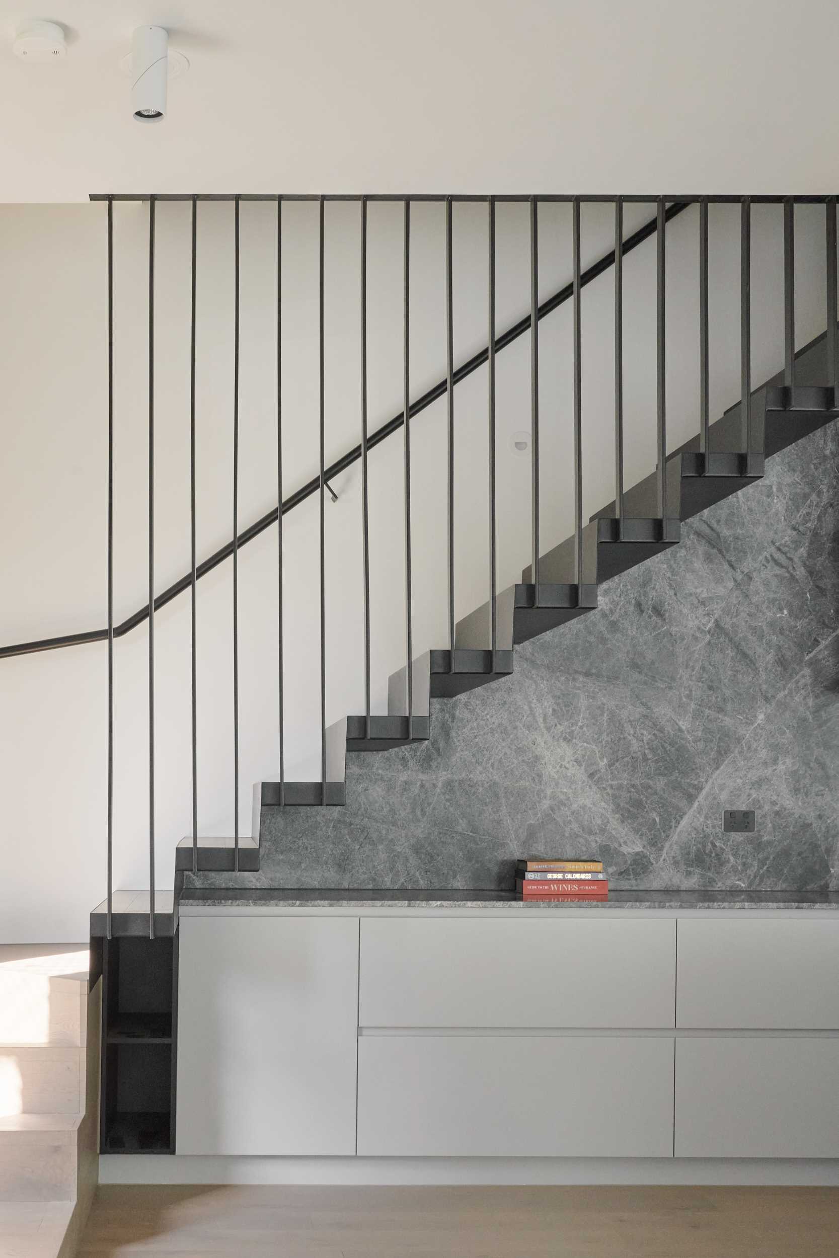Dark colored stairs with matching handrail connects the various levels of this modern townhome, and provides a contrasting element to the neutral interior.