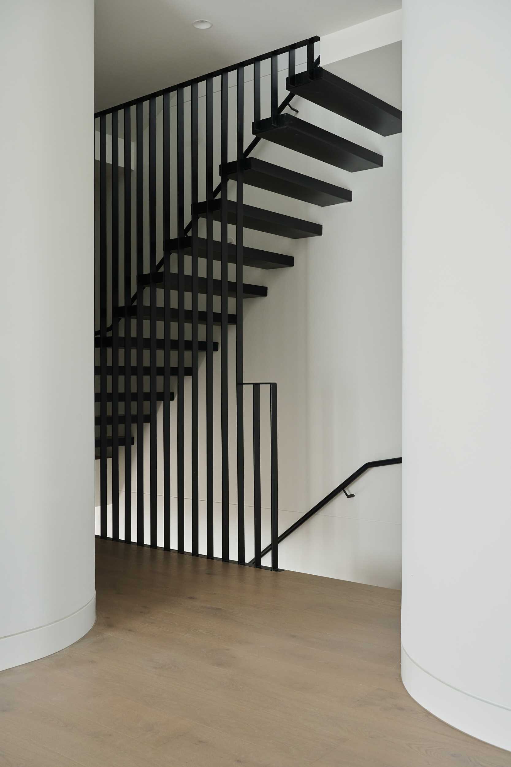 Dark colored stairs with matching handrail connects the various levels of this modern townhome, and provides a contrasting element to the neutral interior.