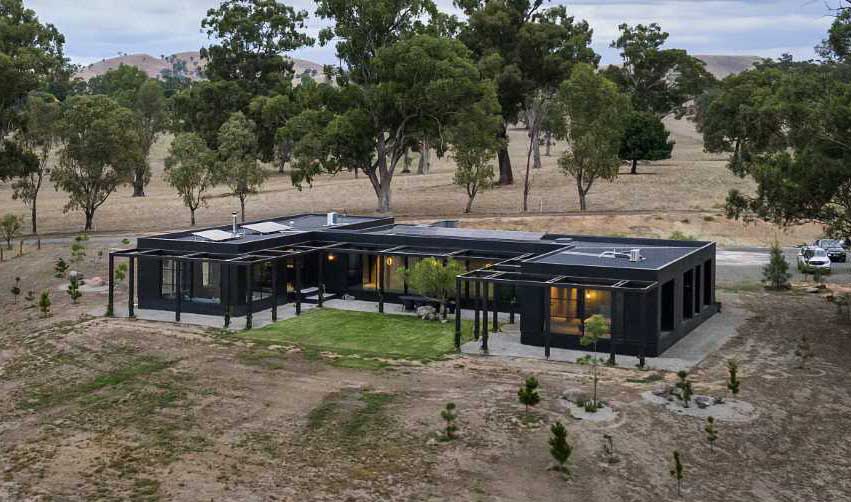 A modern home in a U-shape, includes a black exterior and warm wood accents.