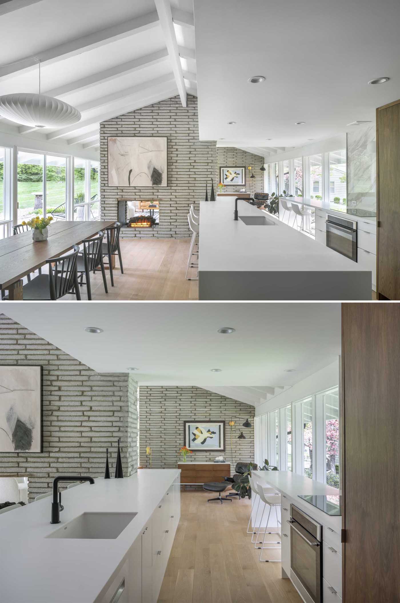 The new kitchen of this renovated mid-century modern home, is bright and open with long white countertops, wood cabinets, and a seating area by the windows.