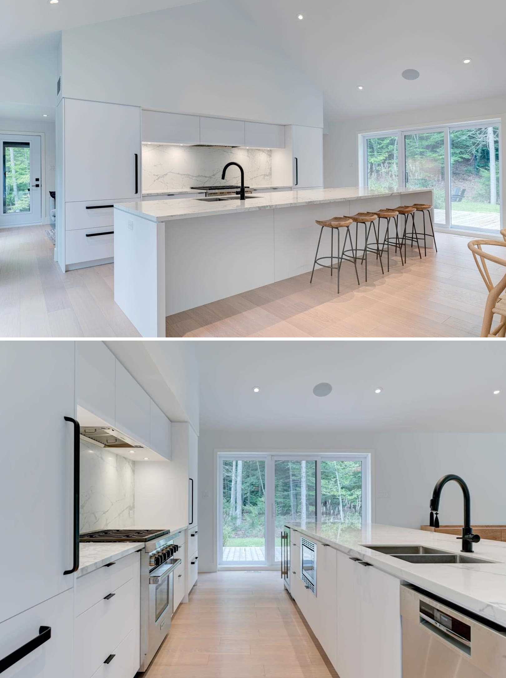 In this modern kitchen, a long island allows for plenty of counterspace, while the light color complements the minimalist white cabinets and integrated appliances. The black hardware and stool legs are contrasting elements.