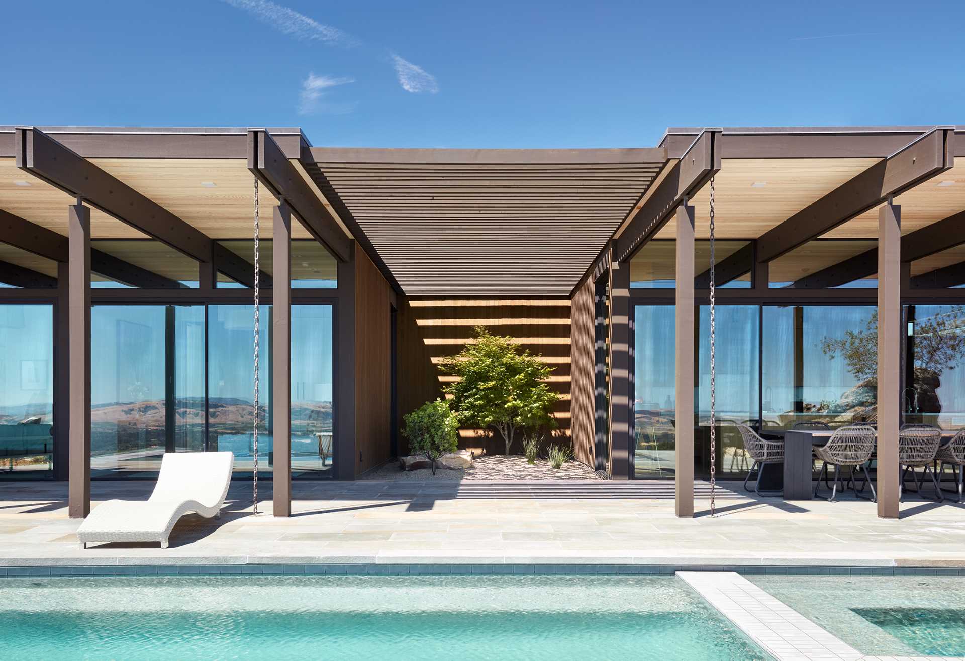 The kitchen, dining, and living spaces of this mid-century inspired home, all open up to a long covered patio, where there's multiple sitting areas, and an additional dining area.