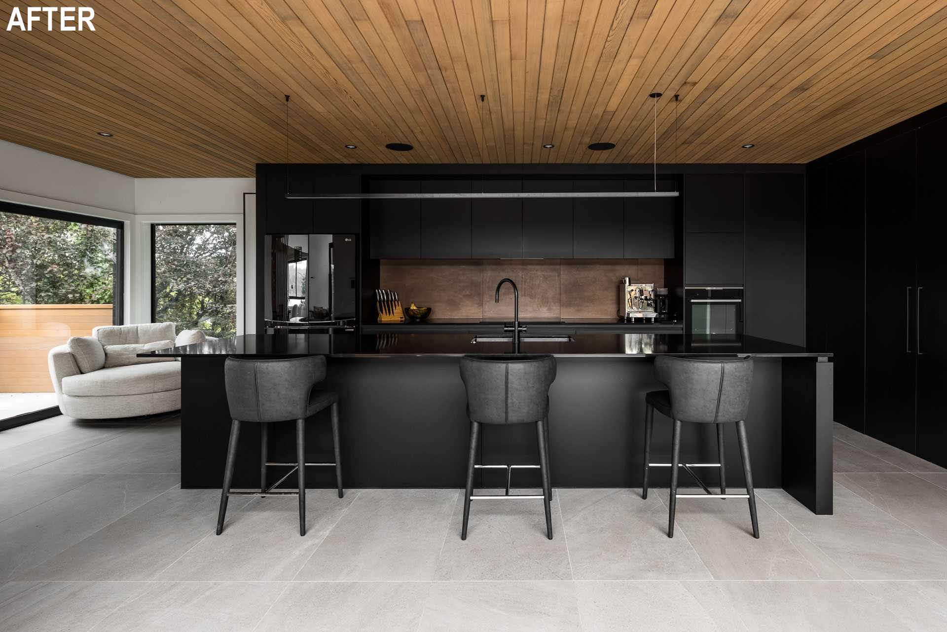 A modern black kitchen with minimalist cabinets, a long island, and a wood ceiling.