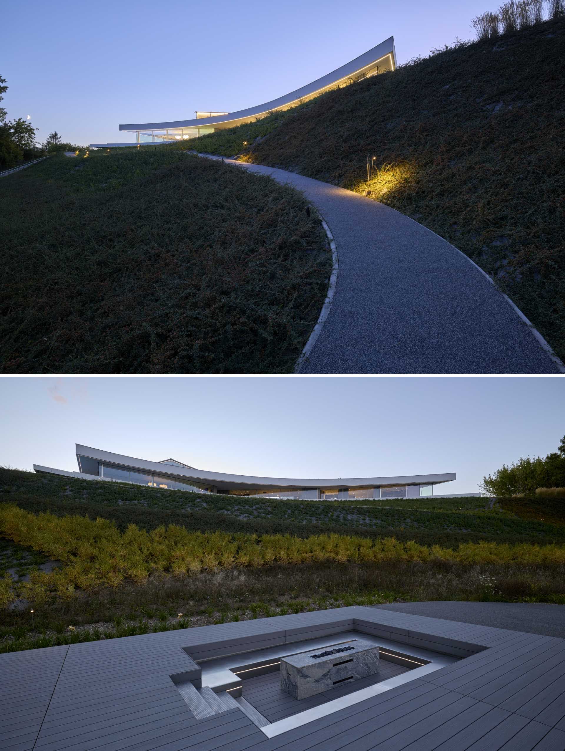 A path from this modern house leads down the hill to a sunken seating area with a firepit.