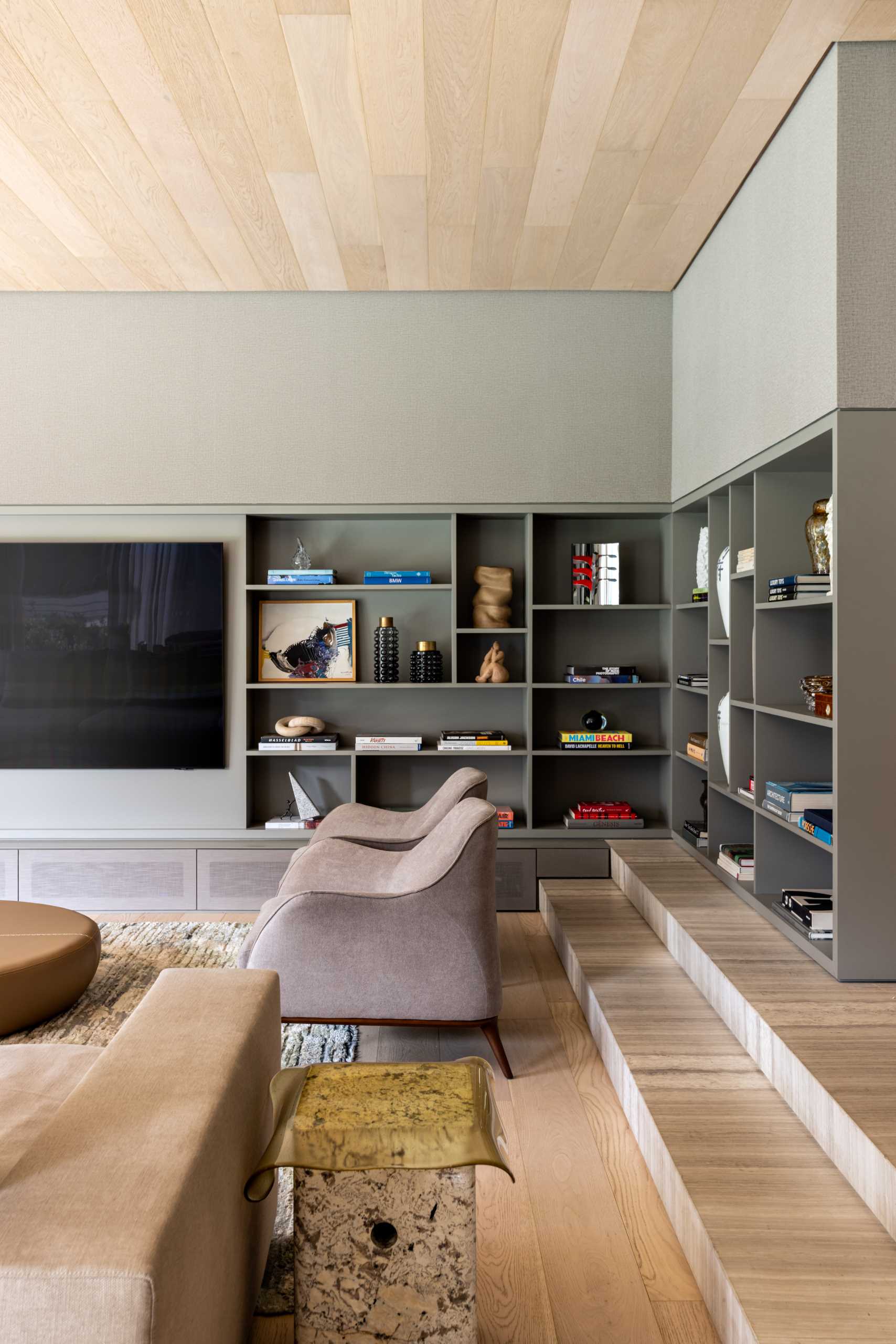 A modern media room with built-in shelving that includes hidden lighting.