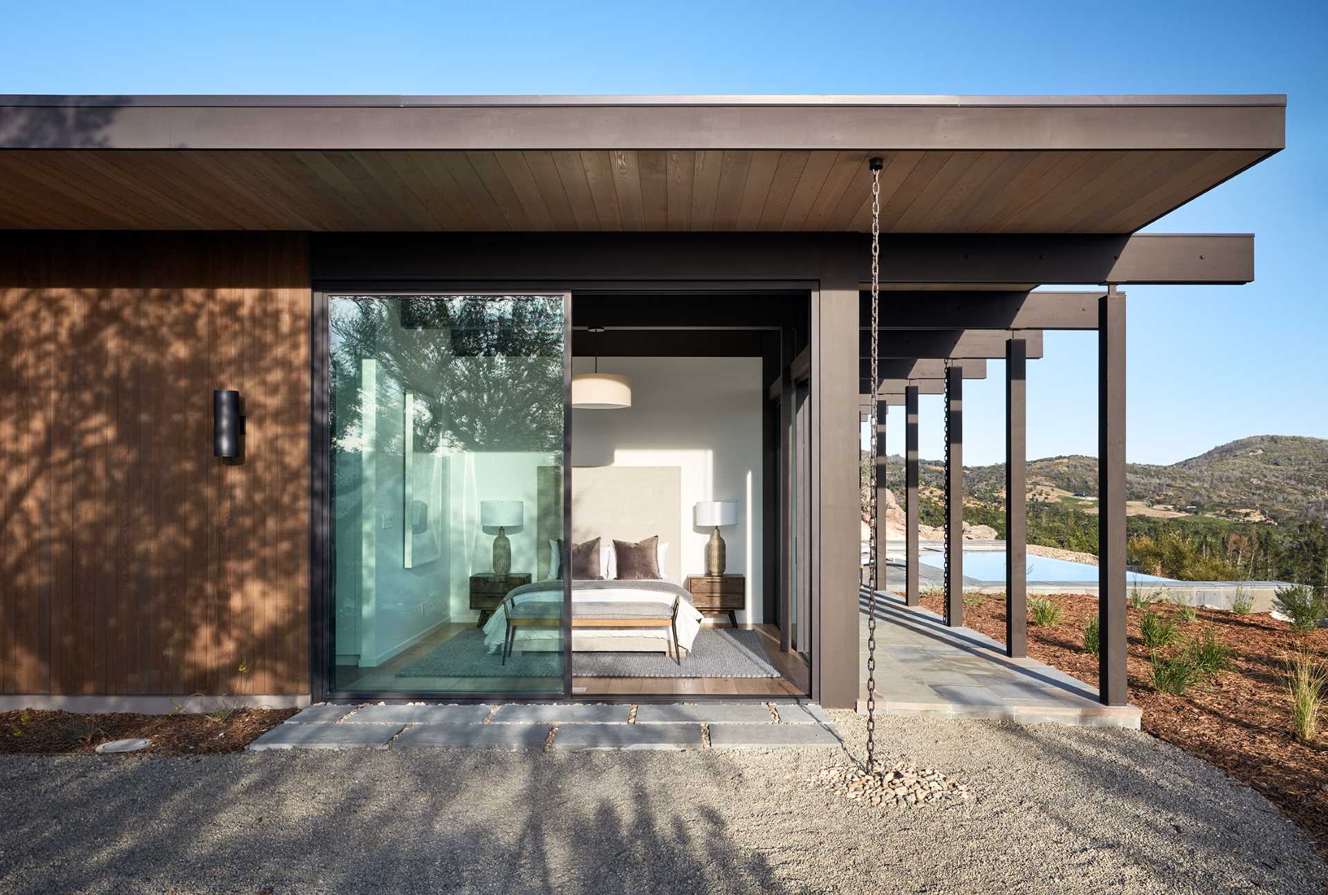 A modern bedroom has sliding glass doors that open to the outdoors.