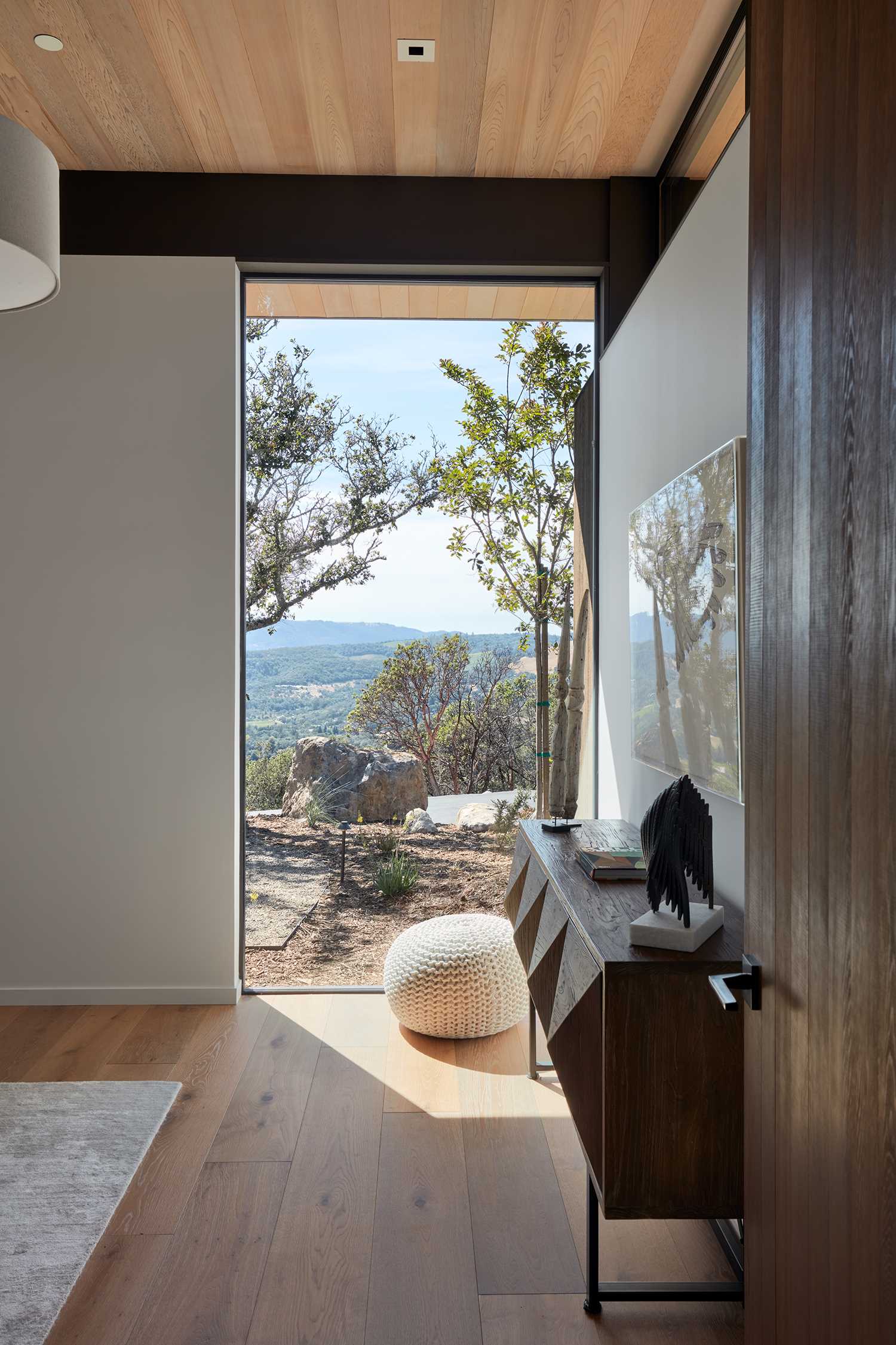 A modern bedroom has a window that perfectly frames the view.