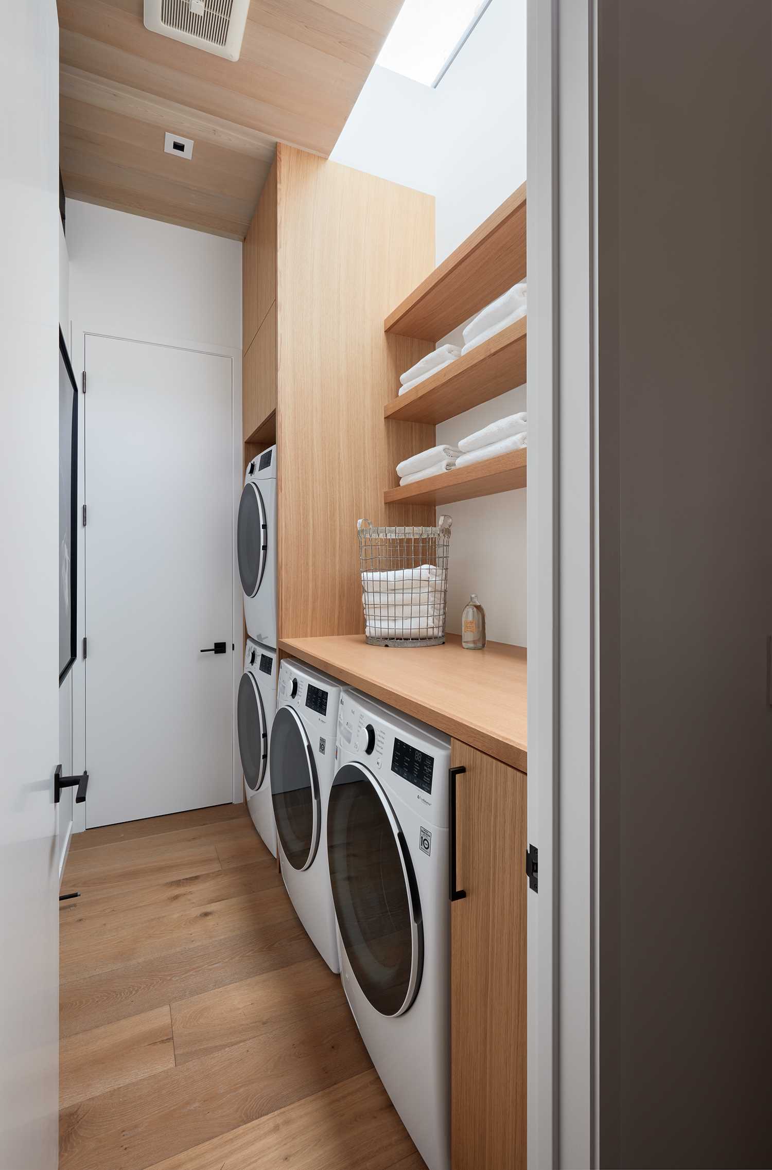 In this modern laundry room, there's custom cabinetry and a skylight.