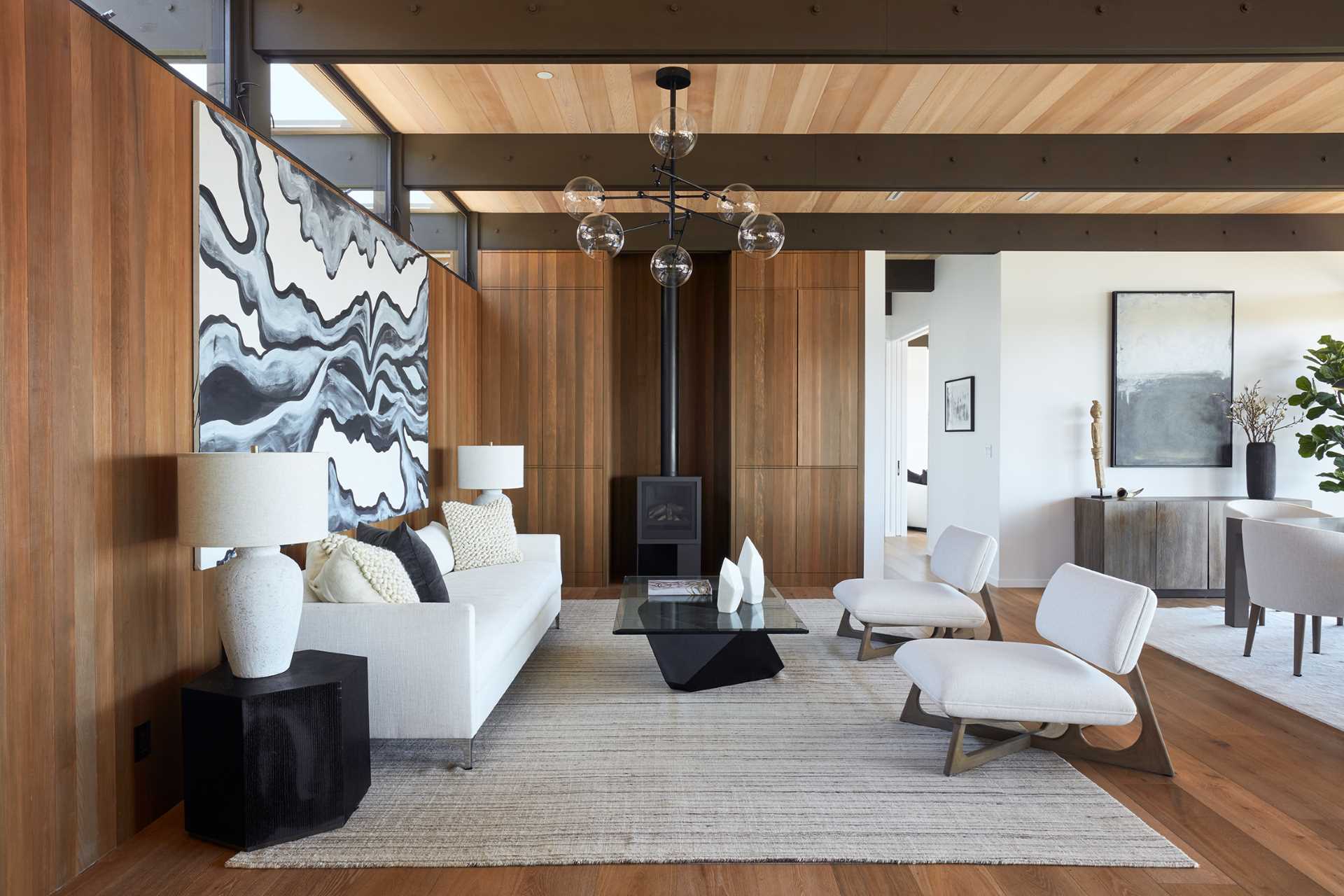 A mid-century modern inspired living room with wood walls, built-in cabinets, and a black fireplace.