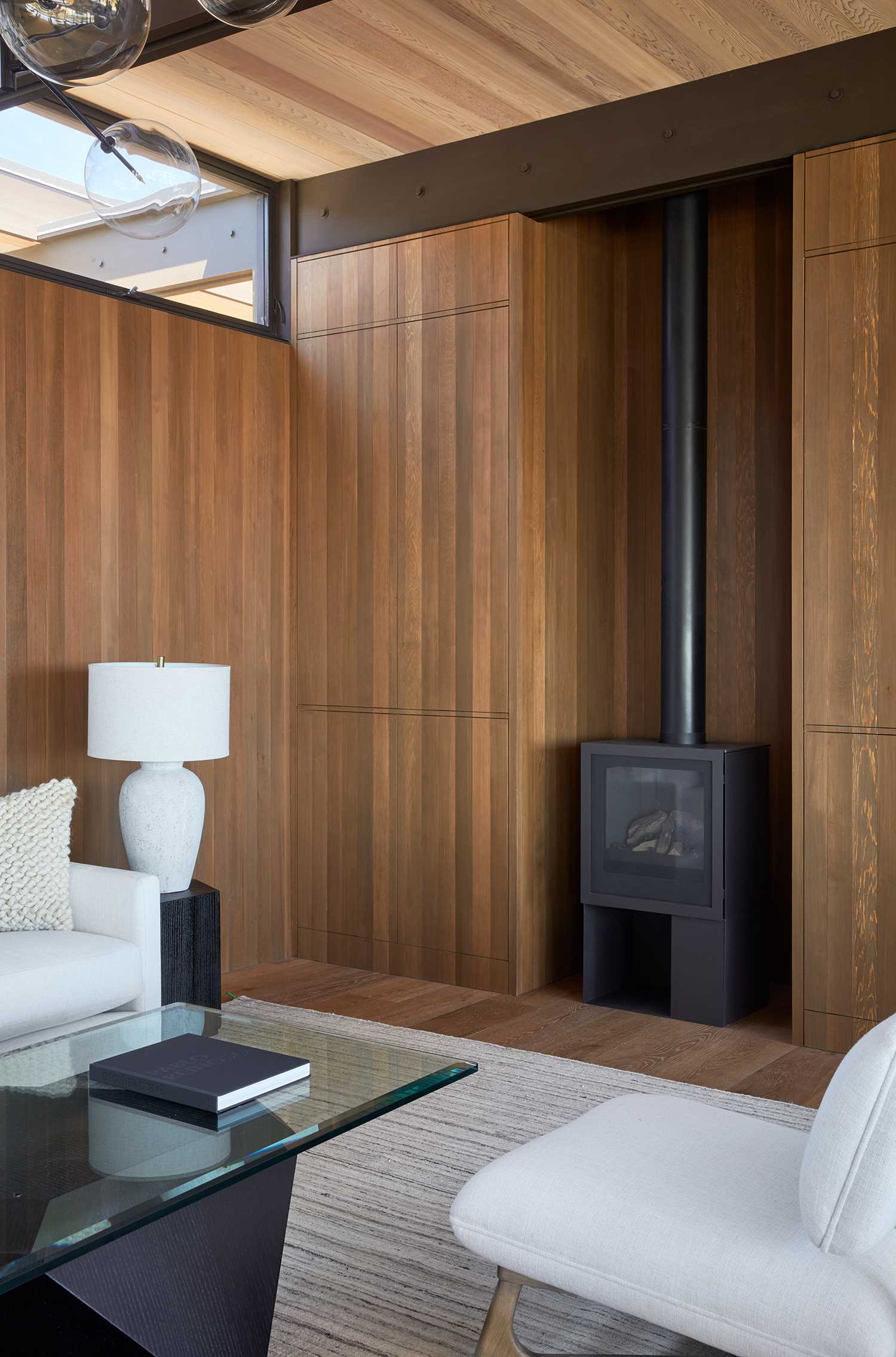 A mid-century modern inspired living room with wood walls, built-in cabinets, and a black fireplace.