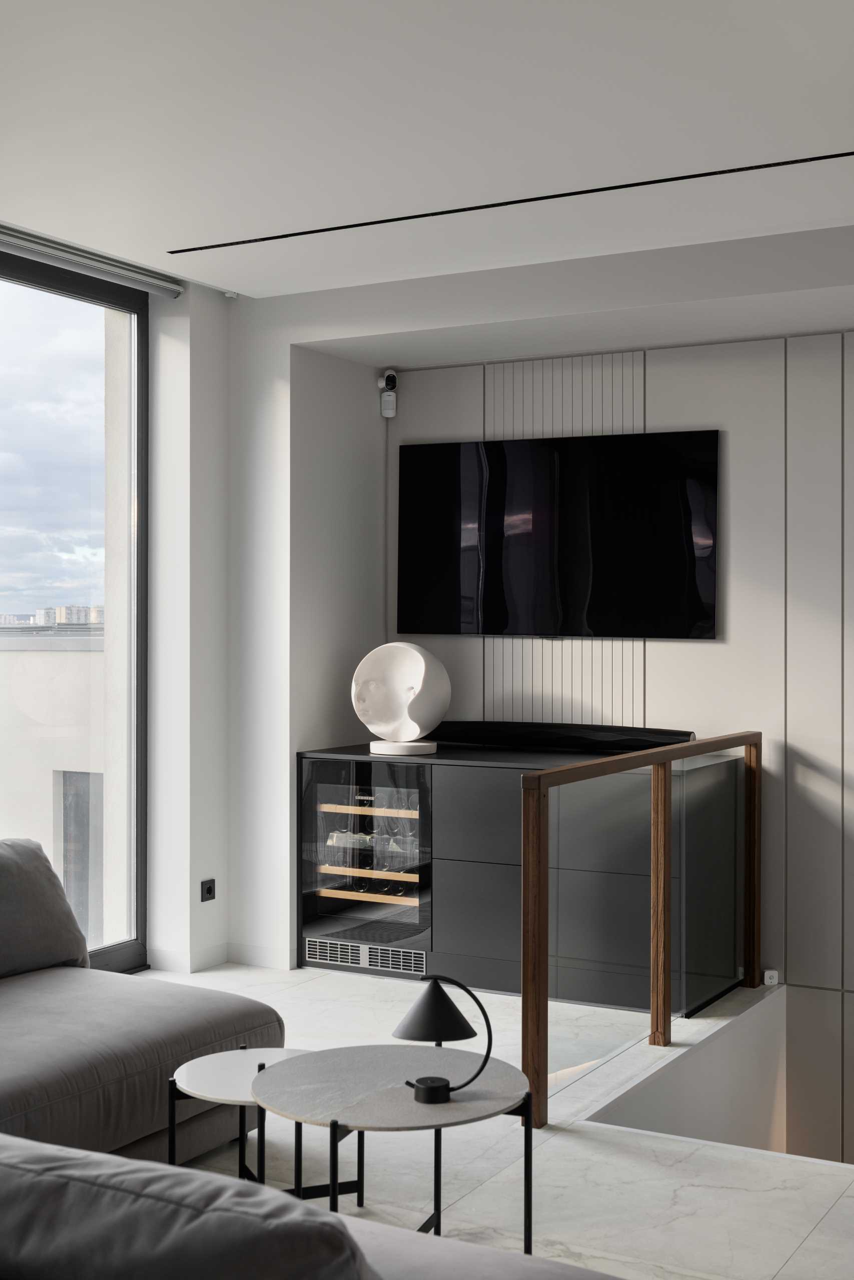 A modern cabinet below the tv includes a window fridge.