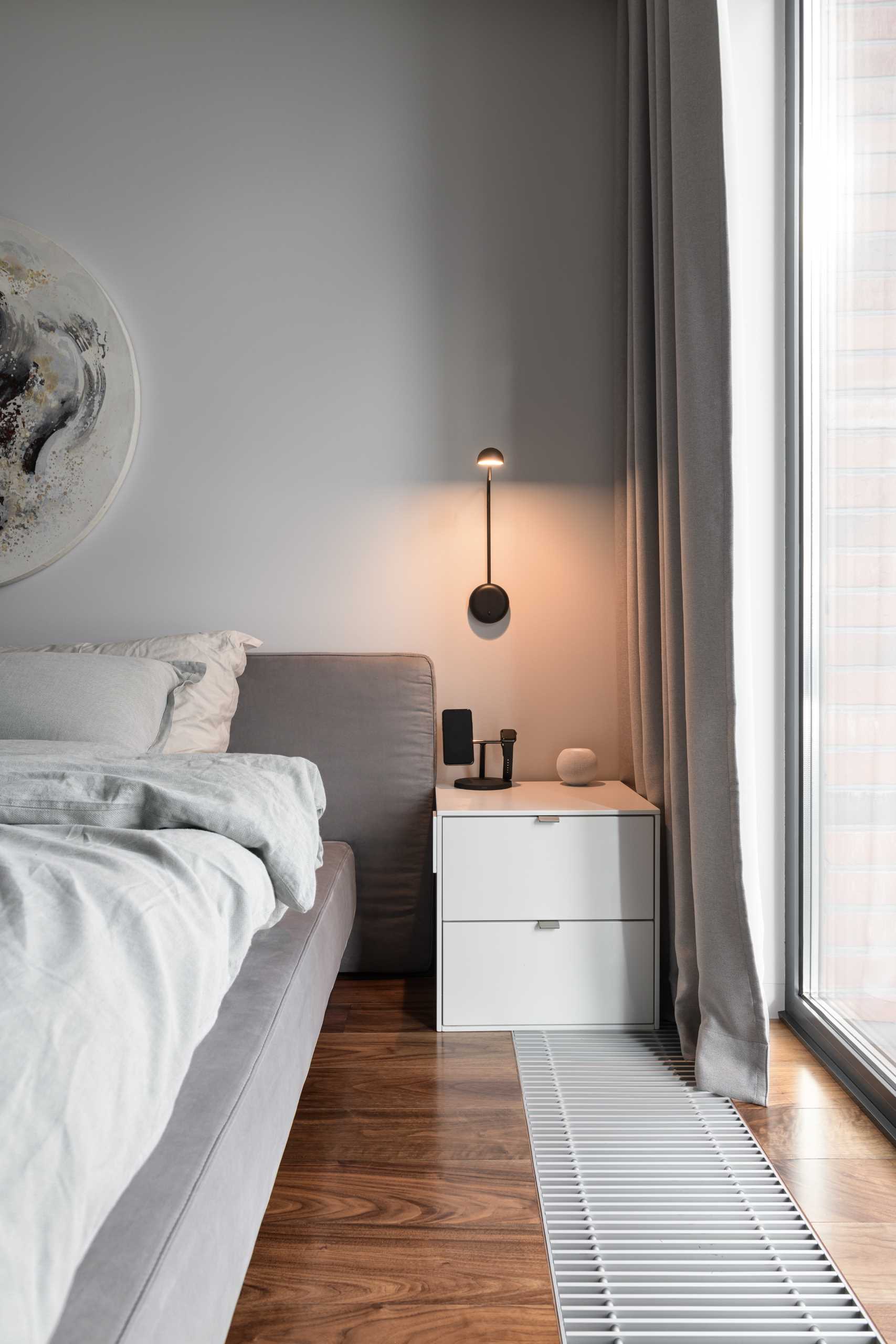 A modern bedroom with a wall-mounted light above the bedside table.