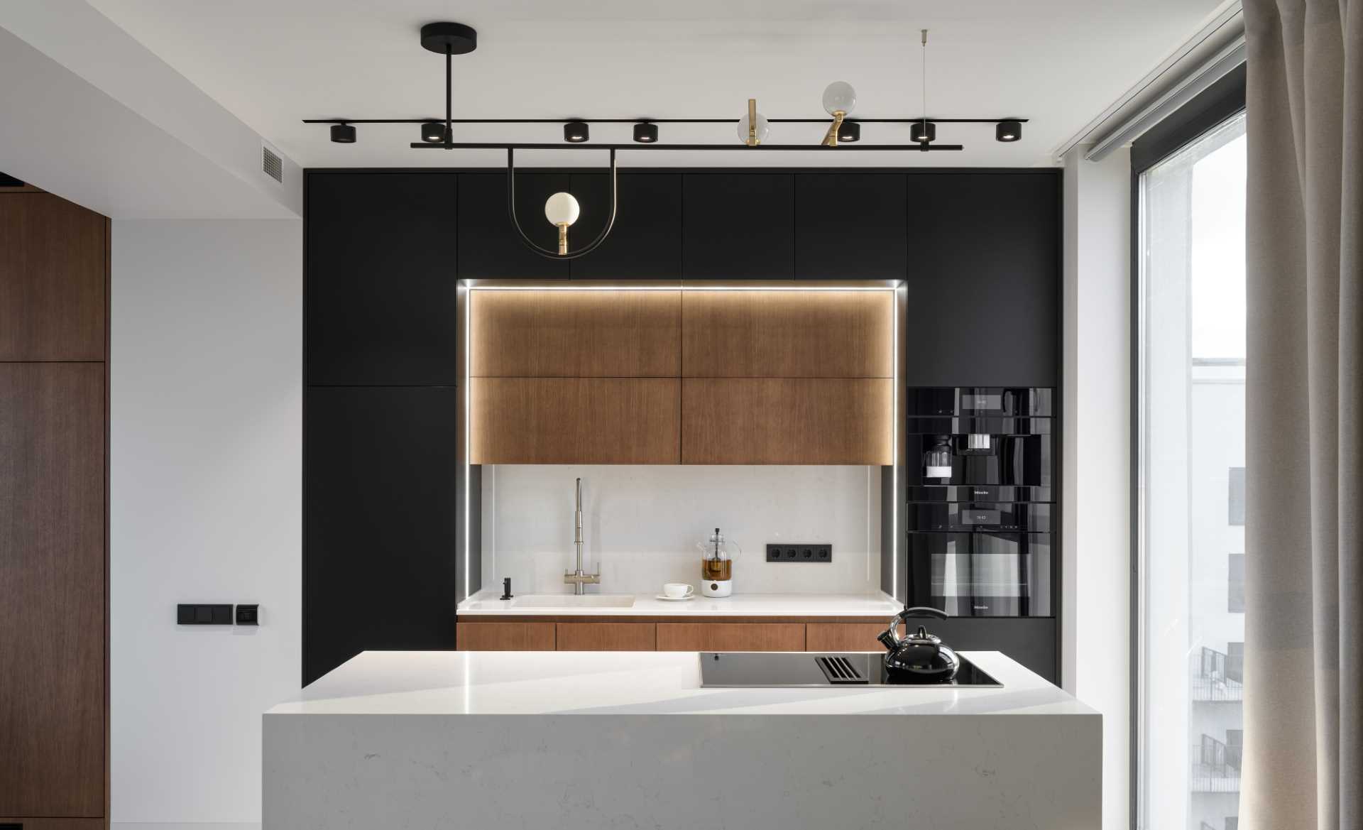 A modern kitchen with black, wood, and white cabinets, and hidden lighting.